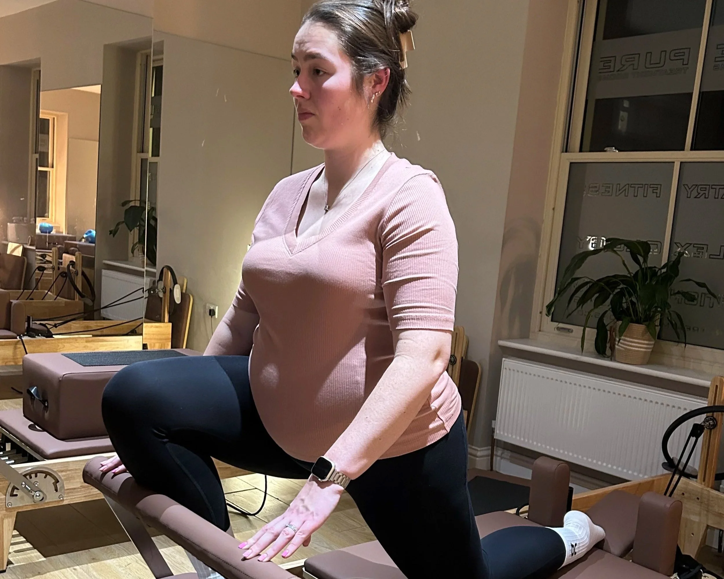 A pregnant woman using a Pilates reformer
