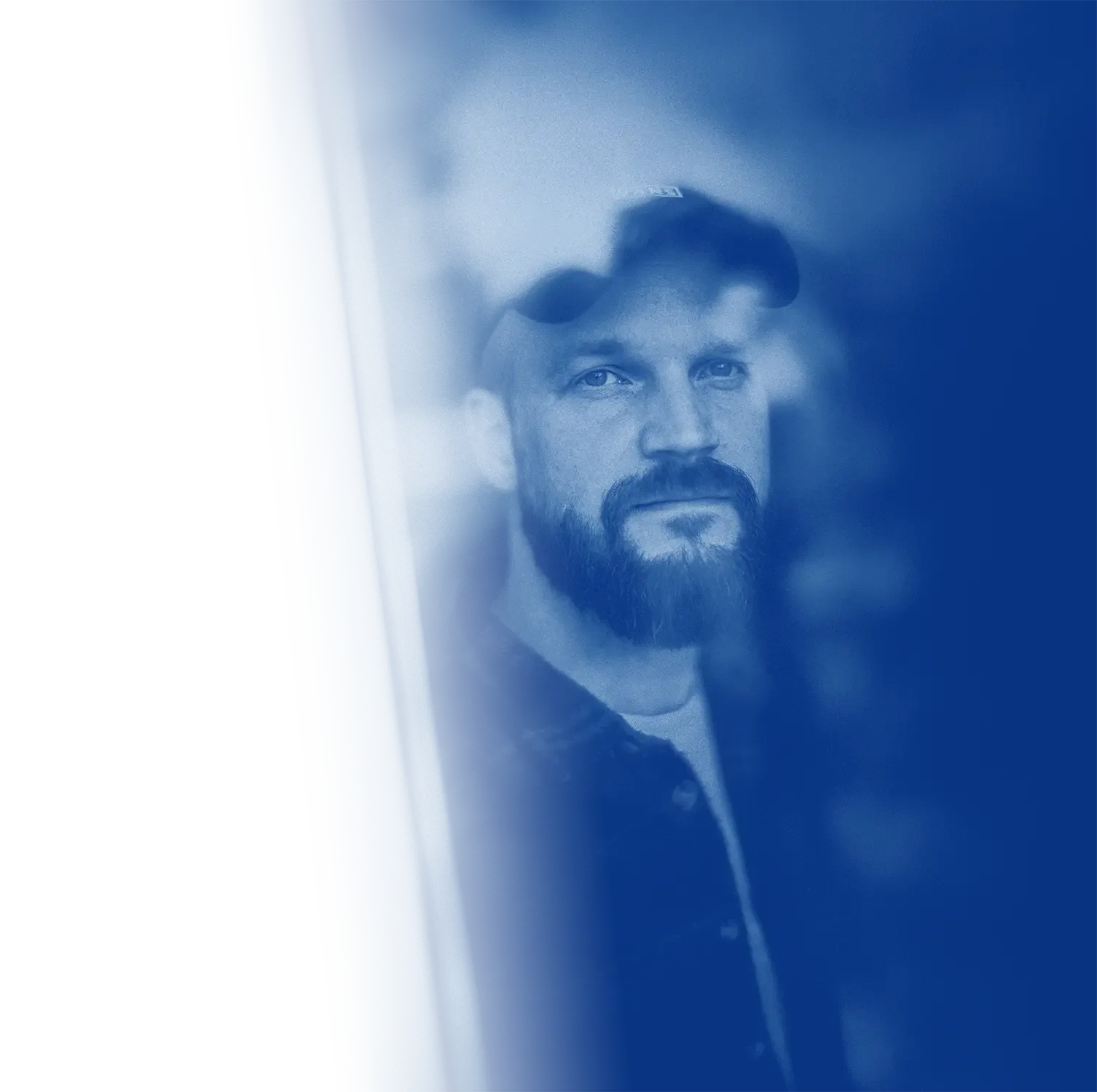 Et portrætfoto af Anders Christensen fra Slomo, der ser ud ad vinduet, fotografiet er farvet blå tone.