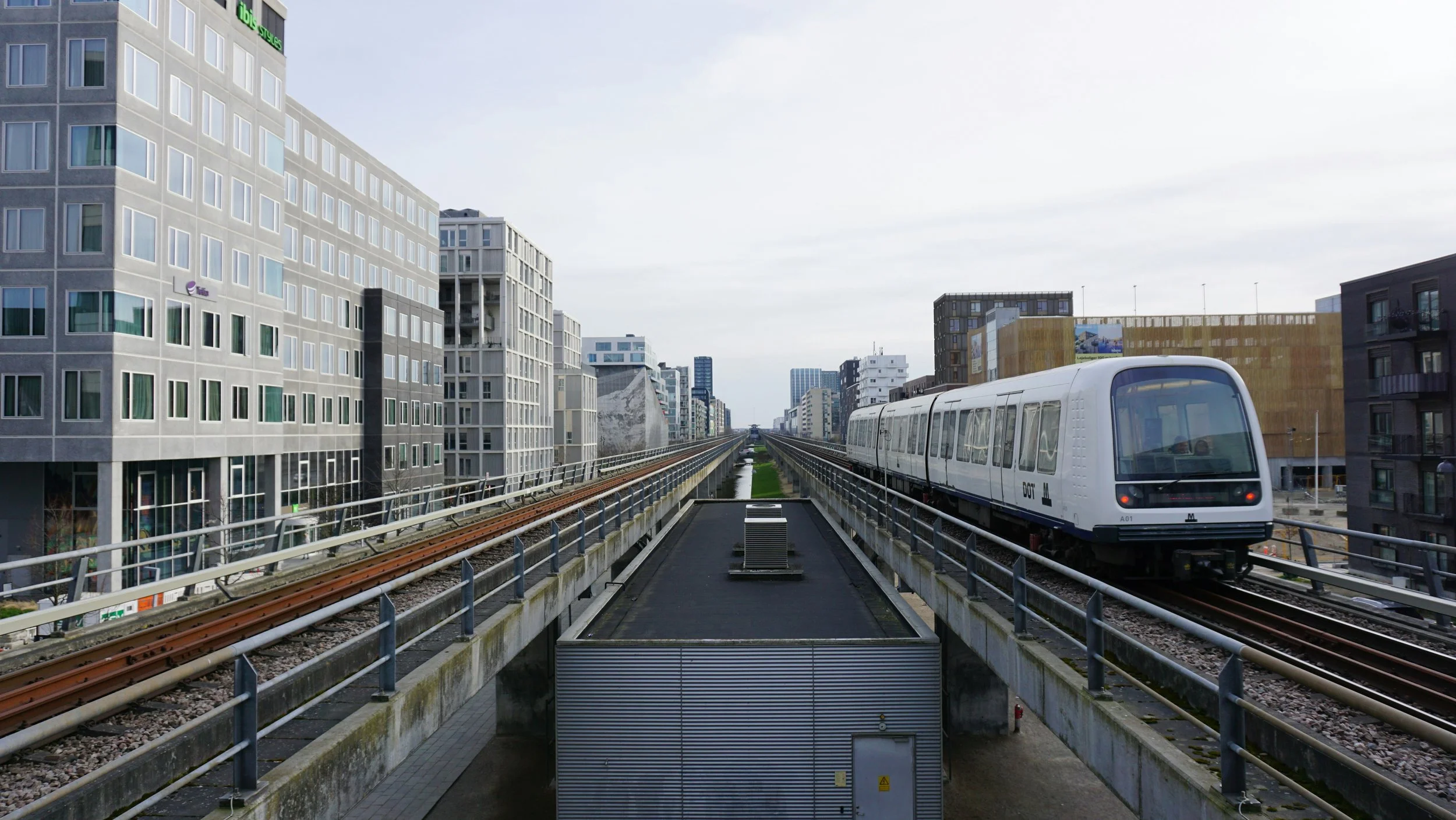Copenhagen metro travelling between tall buildings.