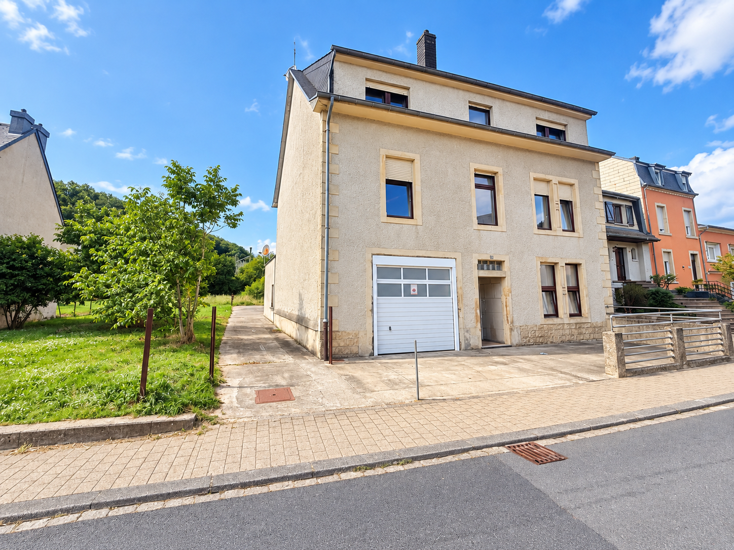 Maison beige sous ciel bleu dans un quartier résidentiel.png
