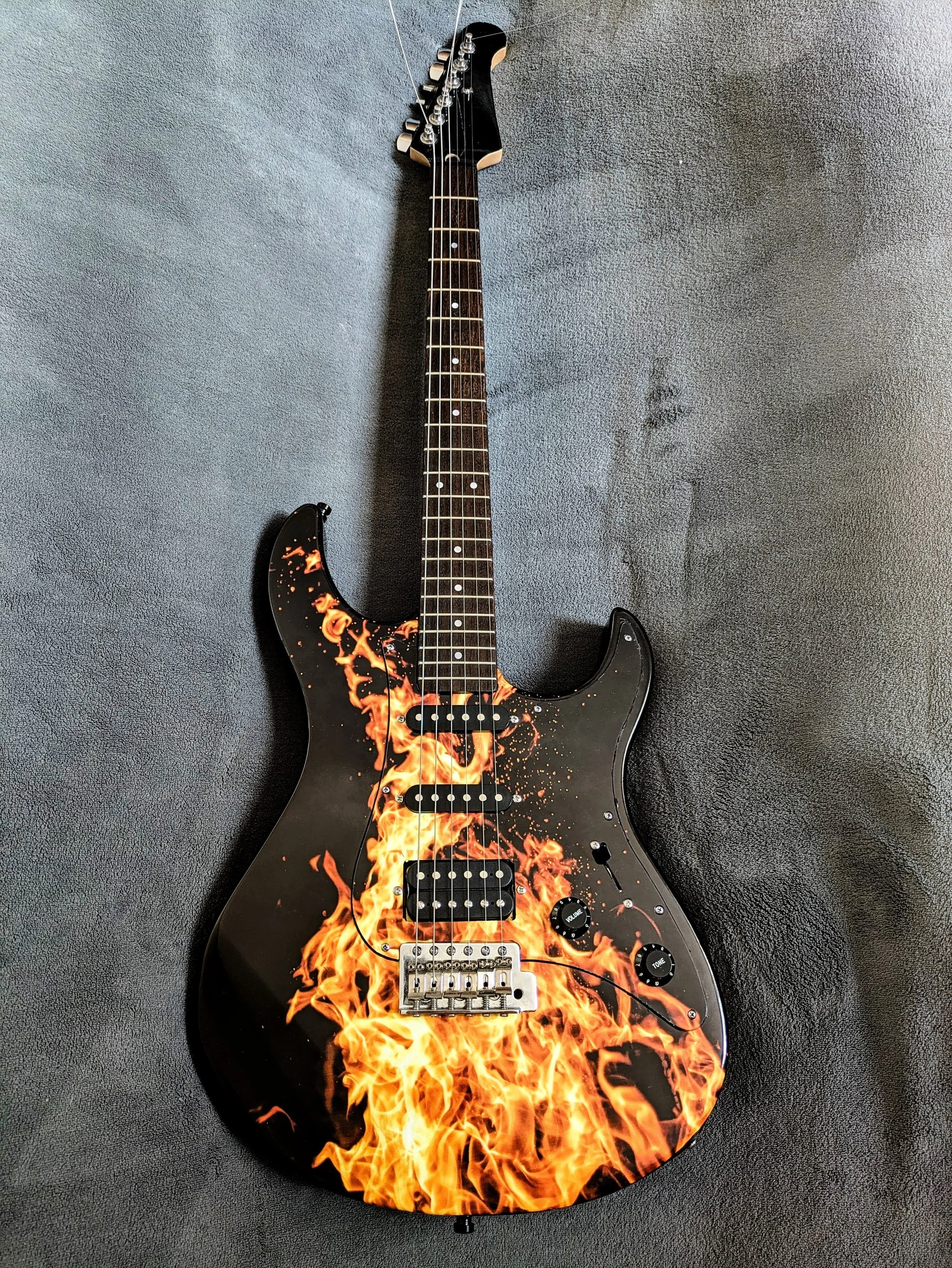 Electric guitar with a black body and flames graphic design on the front.