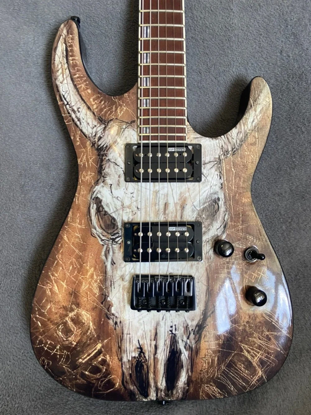 An electric guitar with a custom skull design and graffiti-style markings on its body.