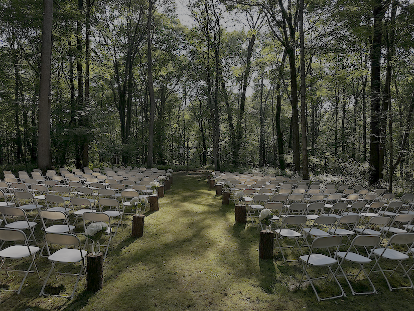 White Folding Chairs setup for a wedding ceremony in the woods