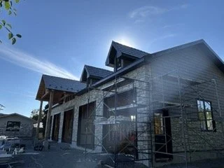 A building under construction with scaffolding on the side, set against a clear blue sky.
