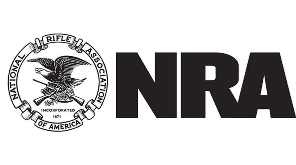 Logo of the National Rifle Association (NRA) featuring an eagle with outstretched wings clutching a rifle, with the text 'National Rifle Association of America' and 'Incorporated 1871' beside large bold letters 'NRA'.