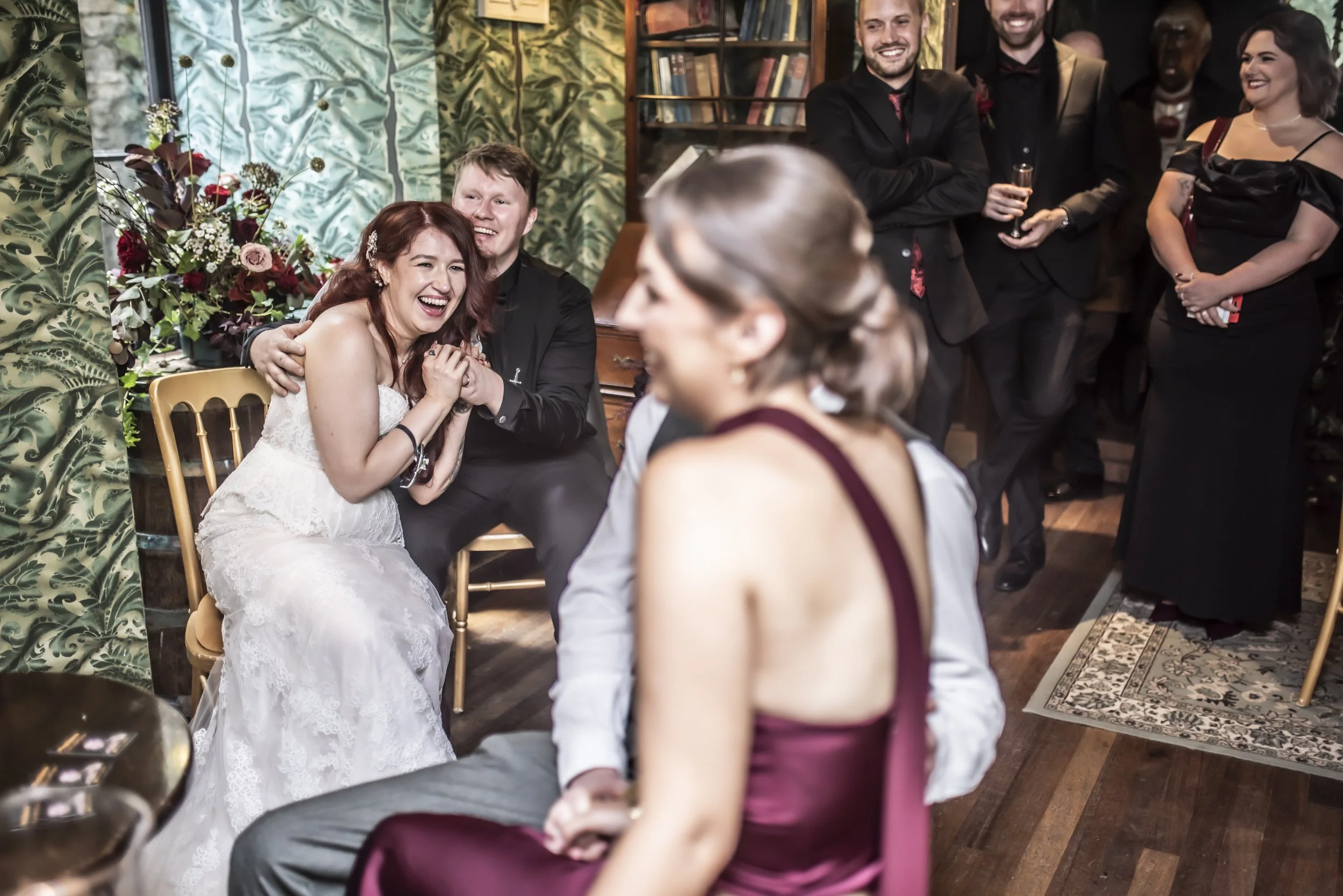 Bride, groom and wedding guests laughing during comedy fortune teller Magdalena’s performance at a wedding in Edinburgh