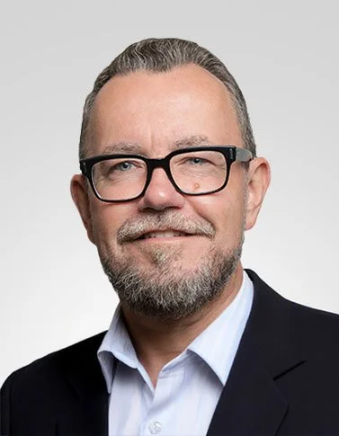 Smiling man in glasses and suit against dark background