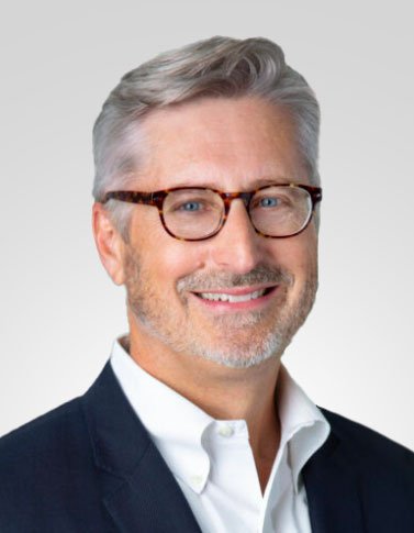 Smiling man wearing glasses and a suit in an office