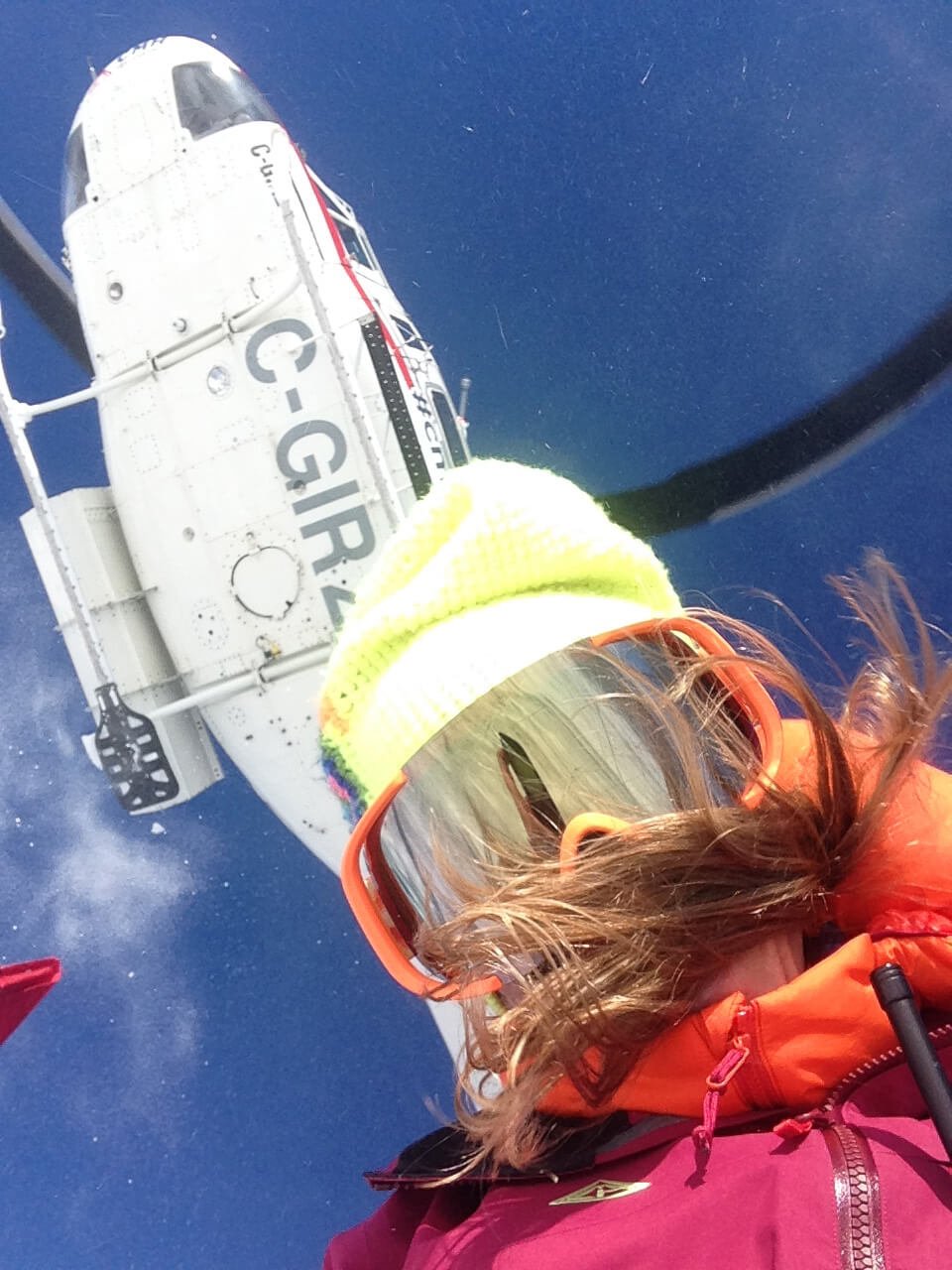 Lyndsay on a heli ski trip with a helicopter behind her
