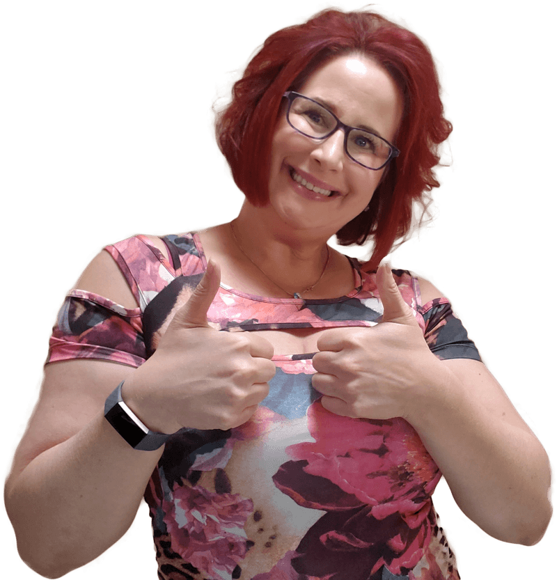 A woman with red hair, glasses, and a floral top smiling and giving two thumbs up.