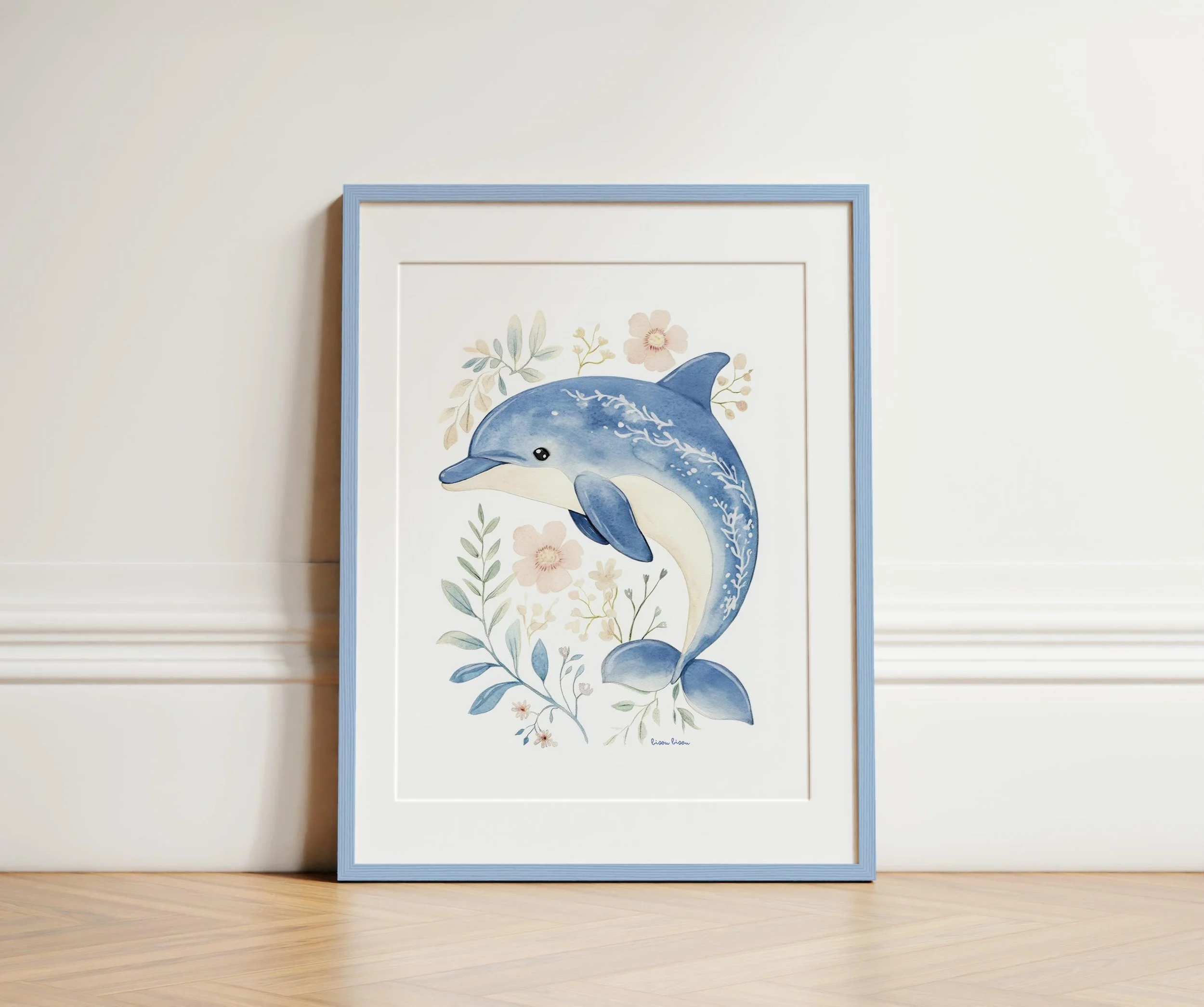 Framed watercolor illustration of a dolphin surrounded by soft pink and green flowers and foliage, leaning against a white wall on a light wooden floor.