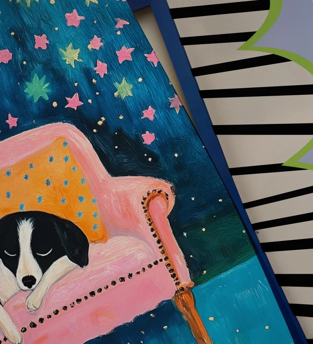 Painting of a black and white puppy sleeping on a pink armchair with a starry night sky background.