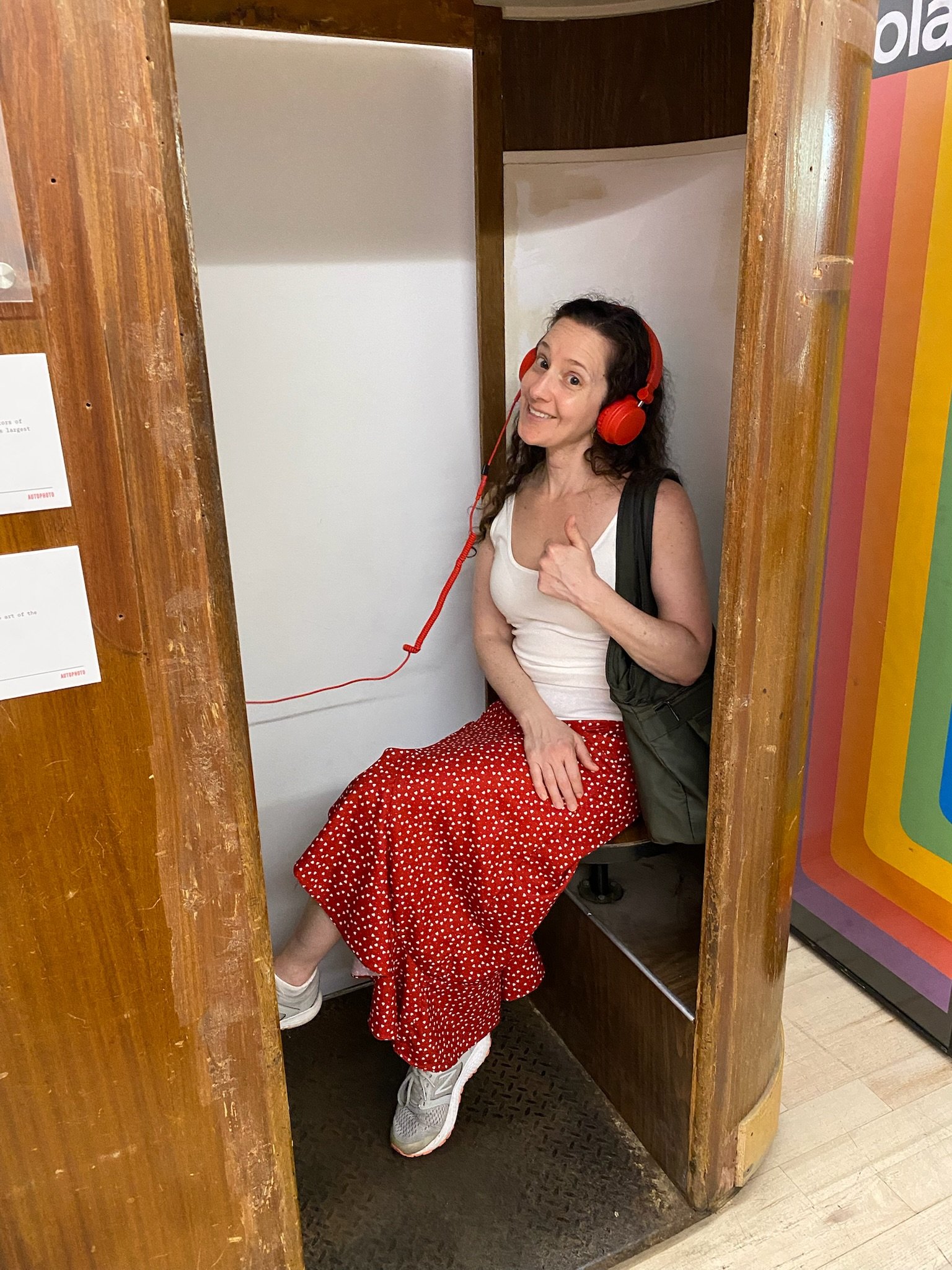 Me sitting in a photo booth wearing red headphones giving a thumbs up