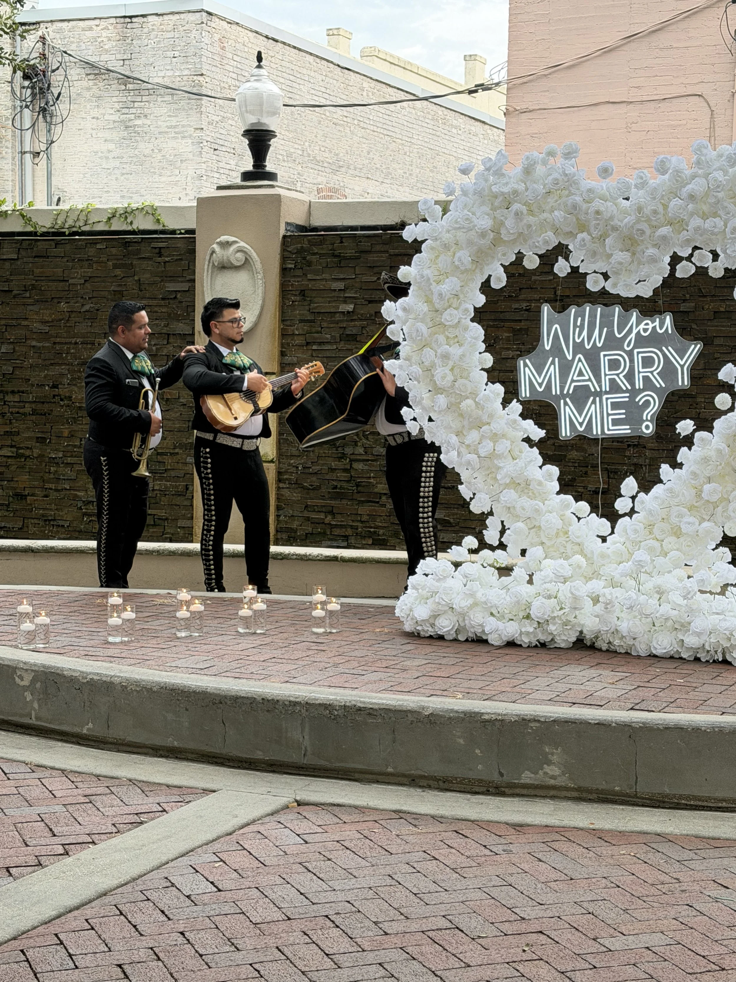 mariachi band at proposal with "will you marry me?" LED lights and flower arrangement