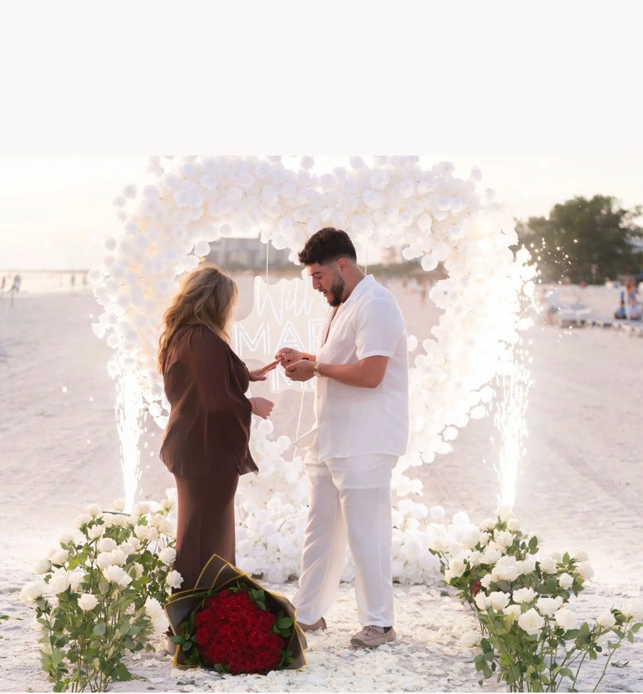 Proposal and engagement setup at Clearwater Beach with flowers and sparklers