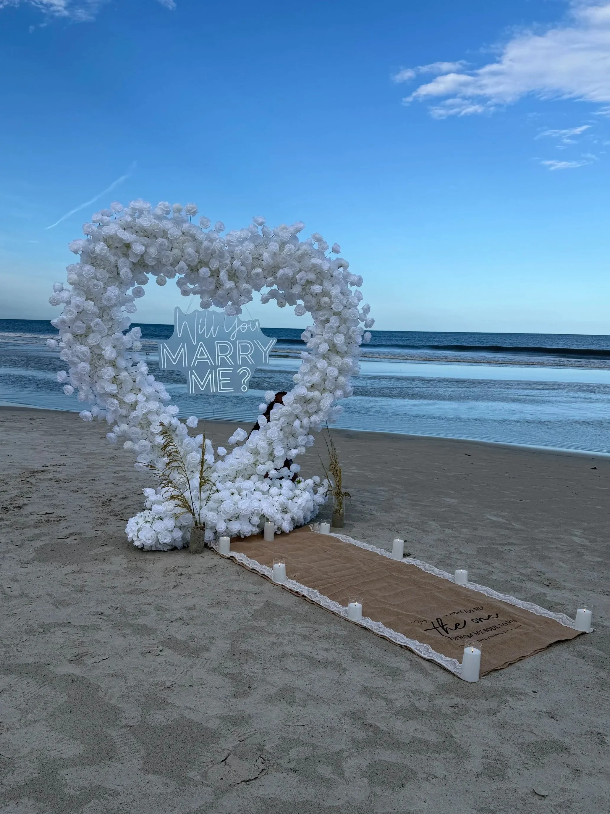 Proposal Setup including a Flower arch and Marry Me LED Sign