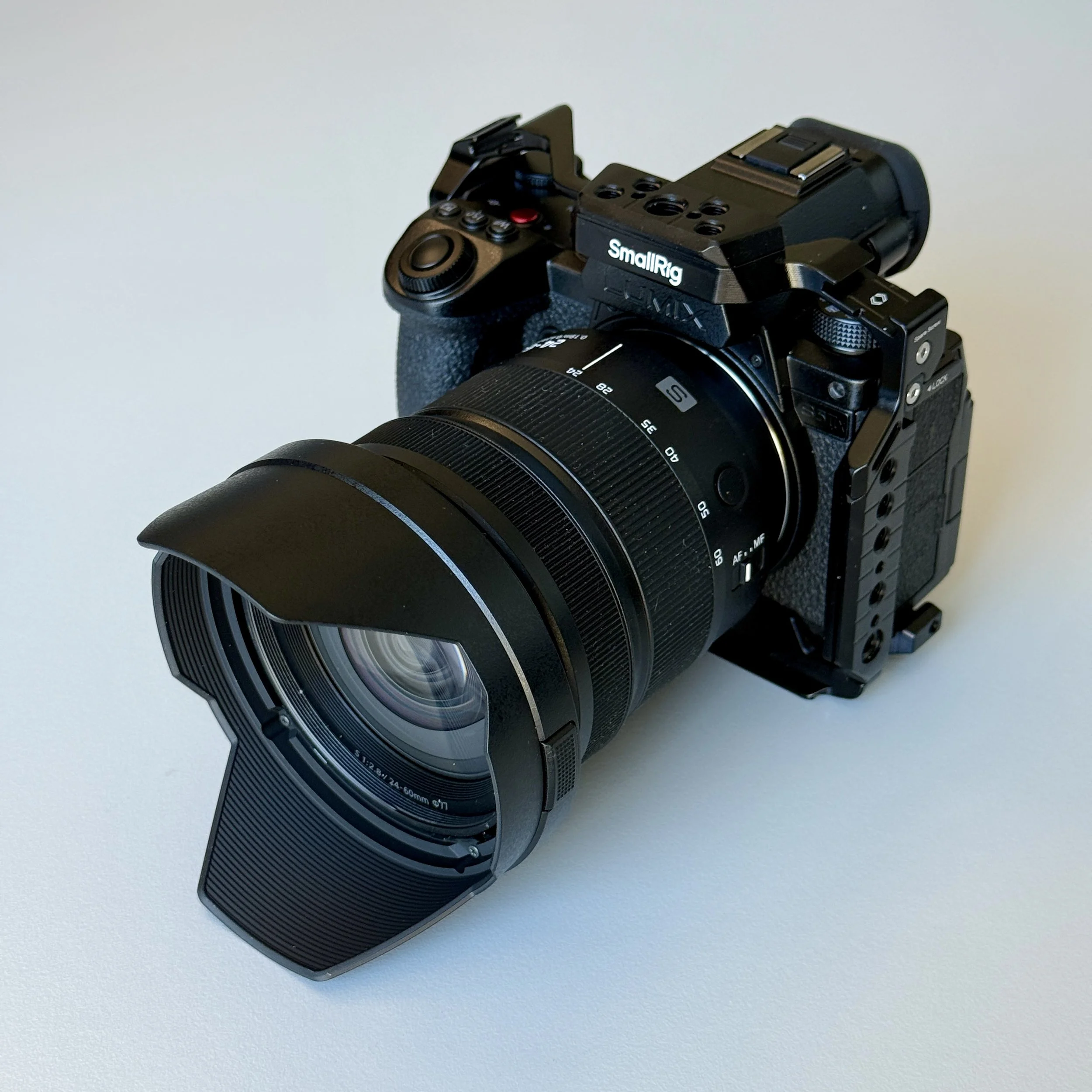 A professional camera with a large lens and lens hood on a white surface.