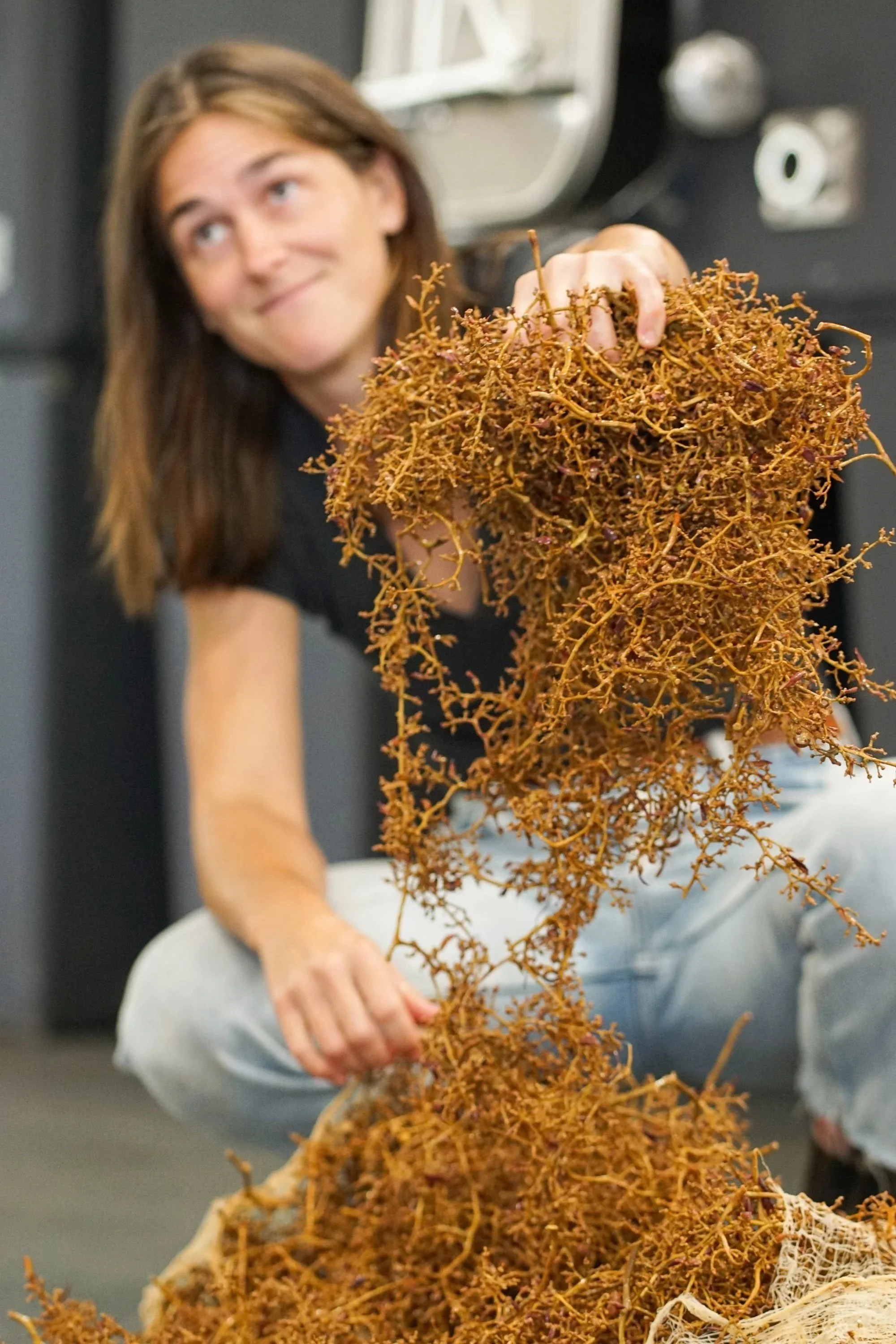 A woman holding a large bunch of dried, orange-brown seaweed.