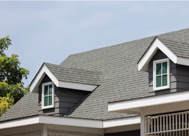 Close-up of a house roof with gray shingles and small dormer windows with white frames.