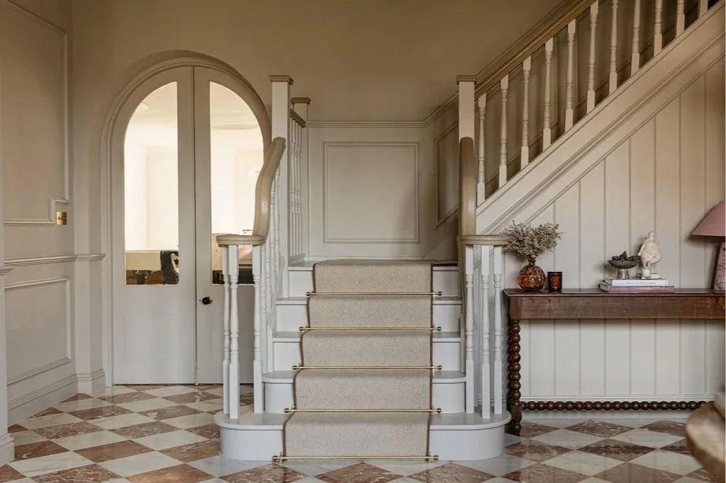 staircase brass rods console table panelling arched doors hallway entryway hall chequerboard floor