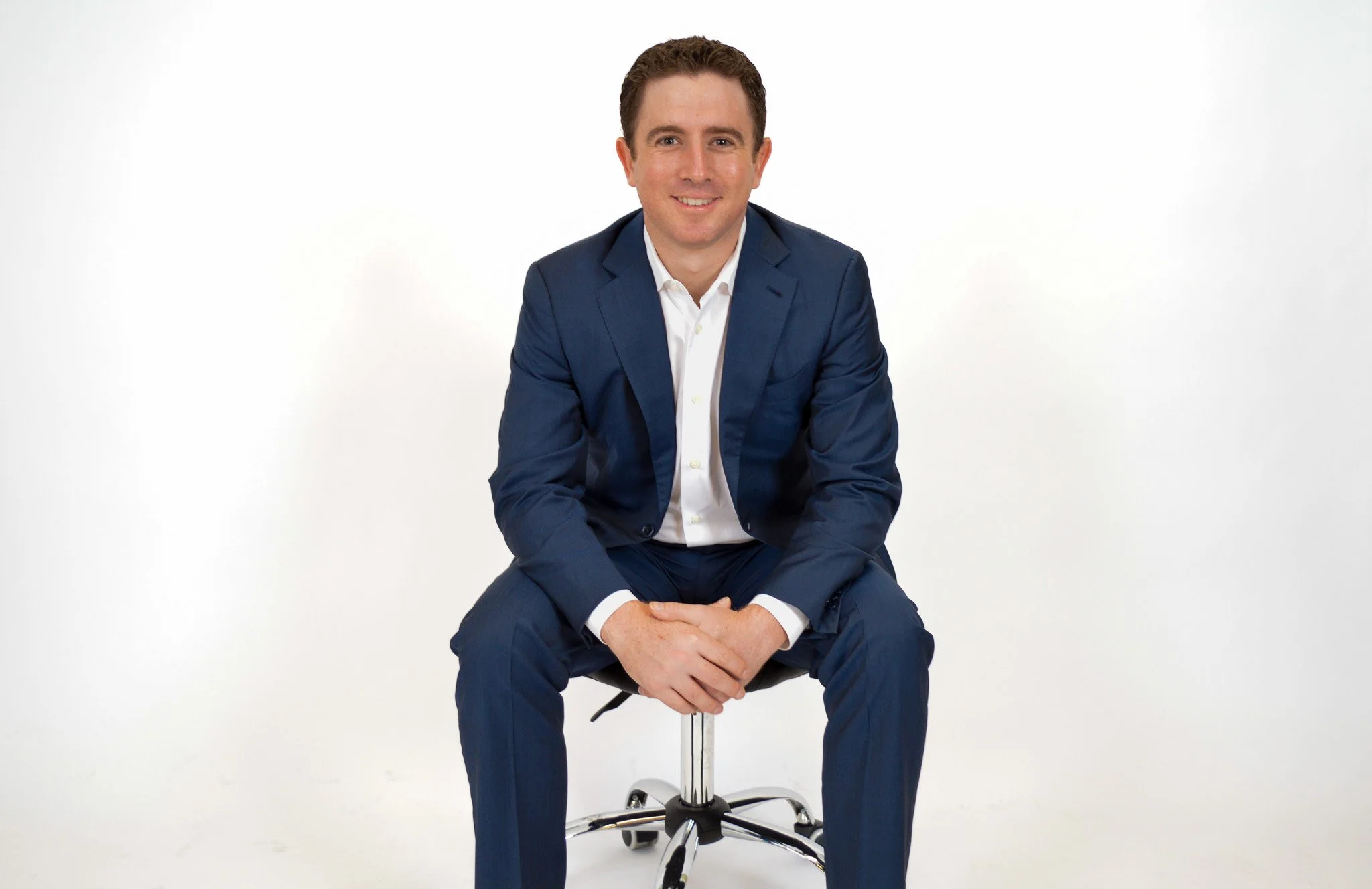 Man in blue suit sitting on a white background