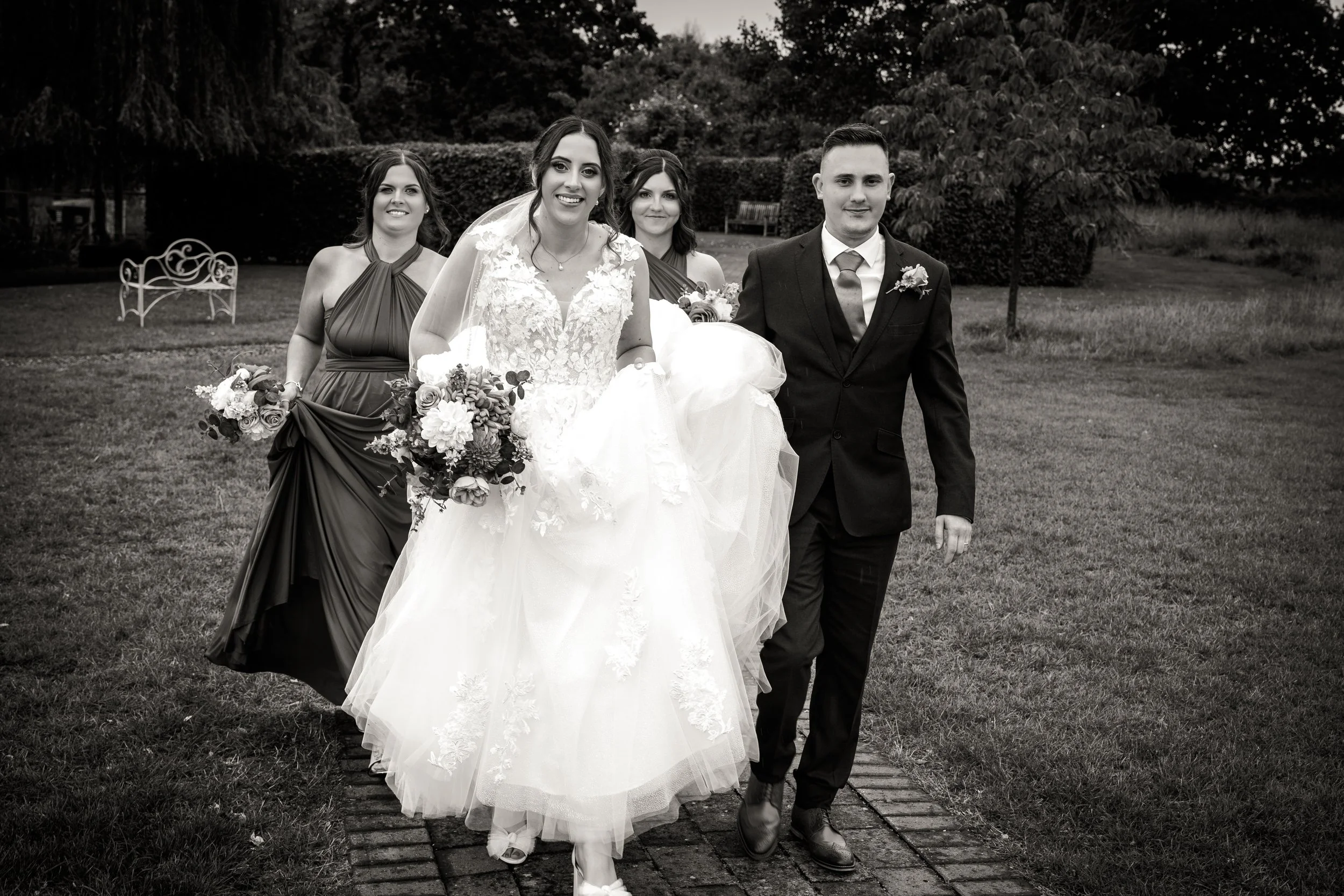 Groom and bridesmaids helping bride with her wedding dress.