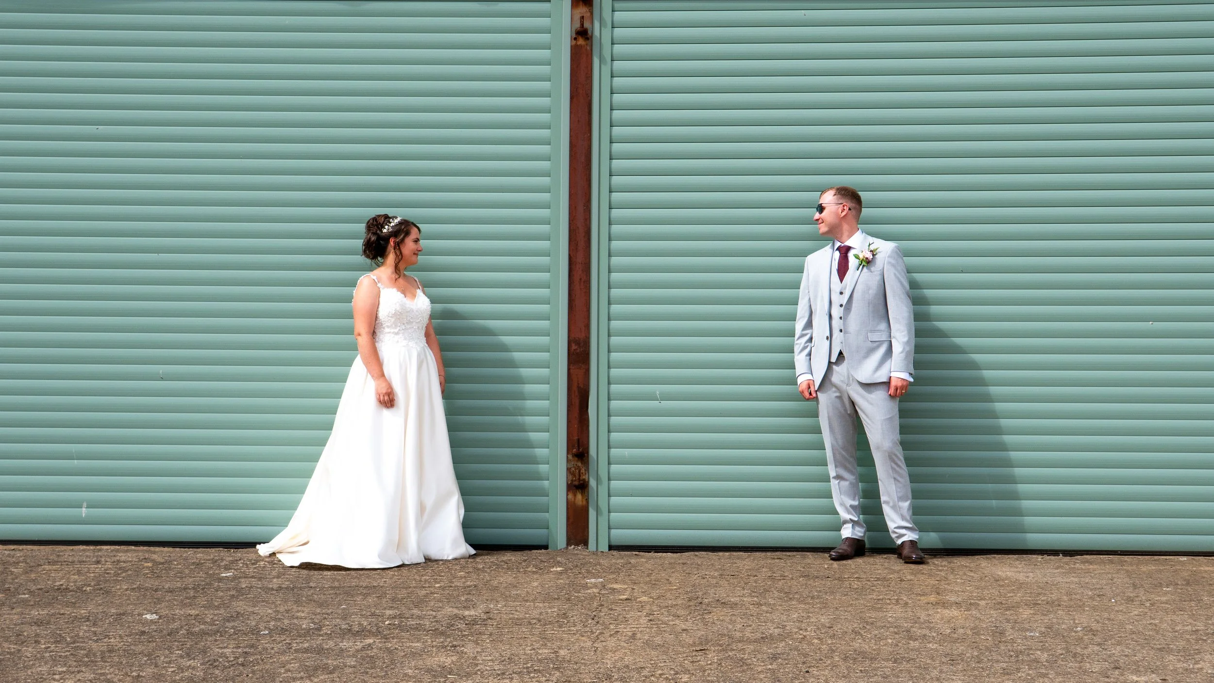 Bride and groom standing by green barn doors.
