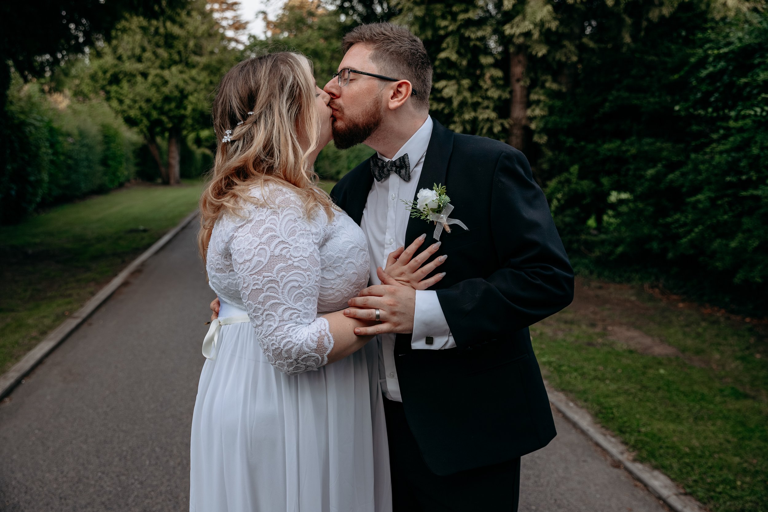 Bride and groom kissing outdoors in a garden setting.