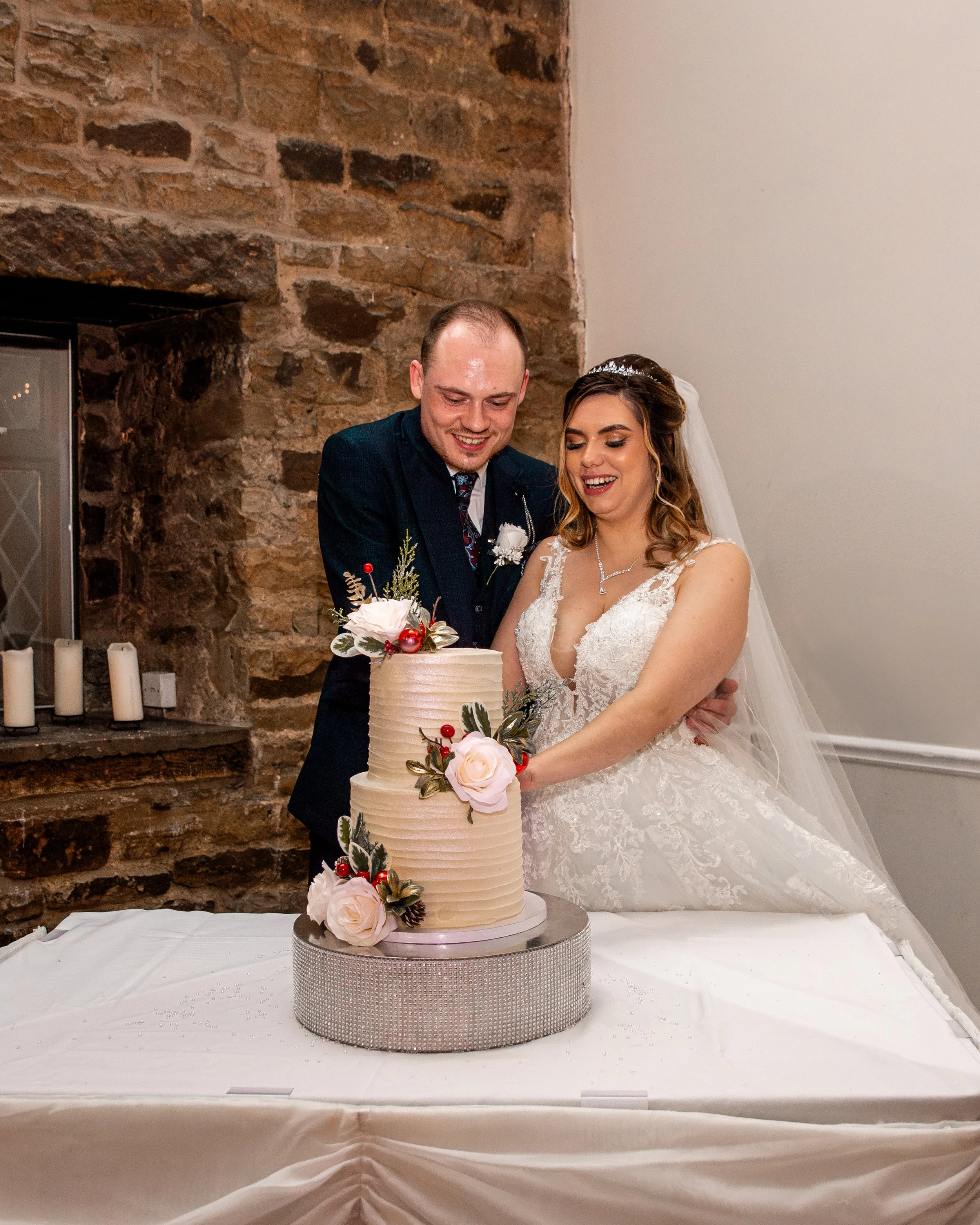 A bride and groom in wedding clothes cutting a wedding cake together.