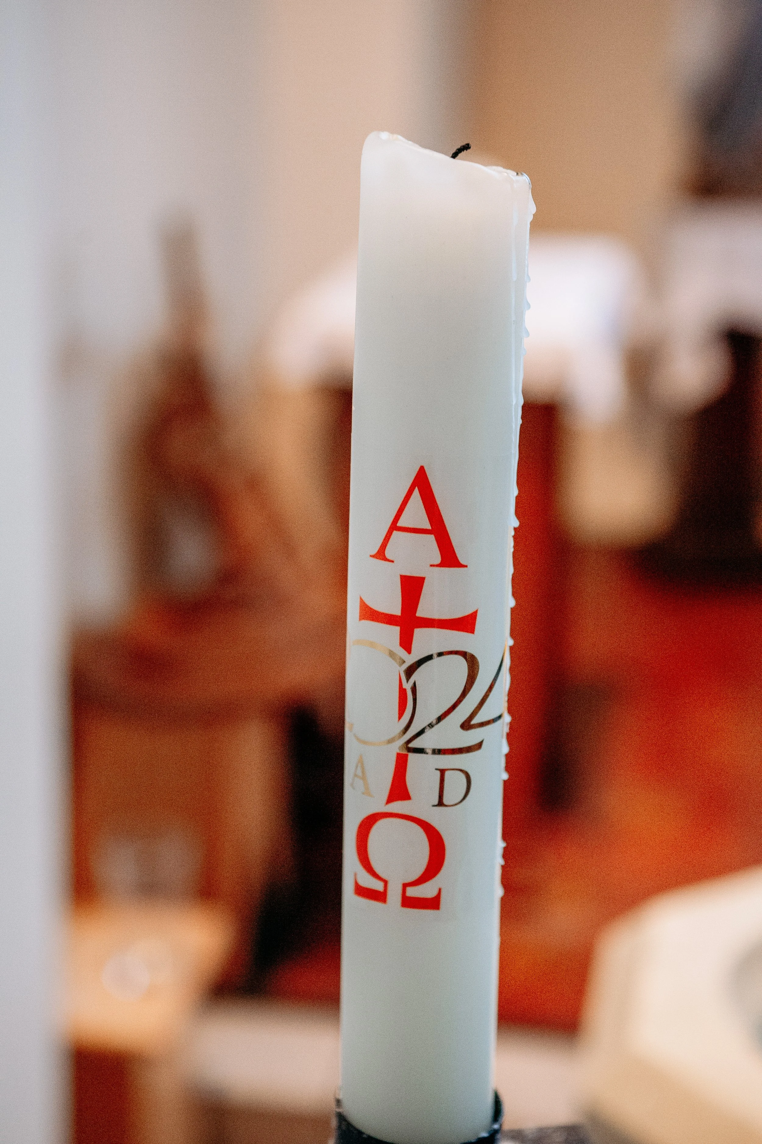Easter candle with Greek letters and numbers, decorated for Easter celebration.