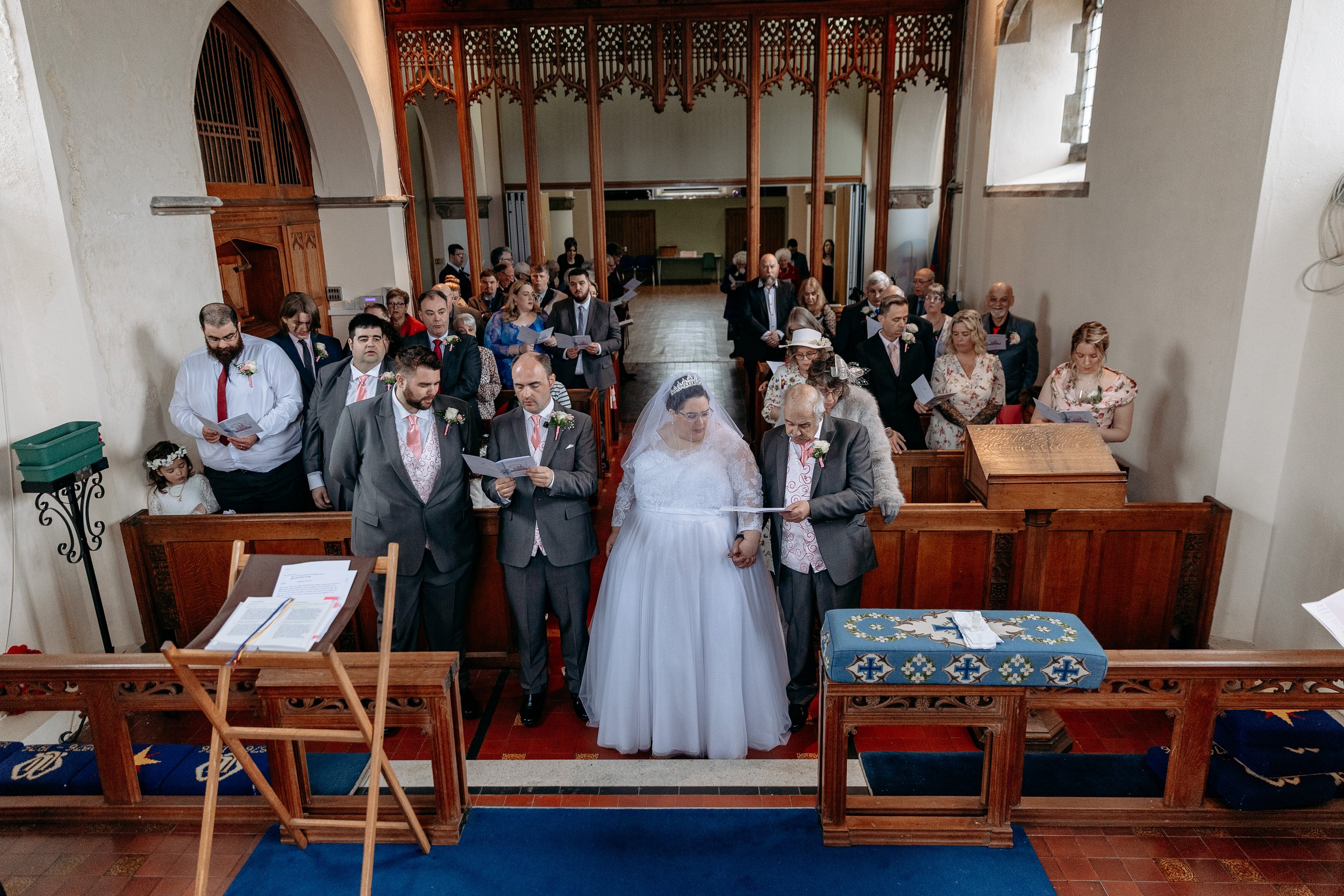 Couple getting married at a church altar with guests seated behind them during a wedding ceremony.