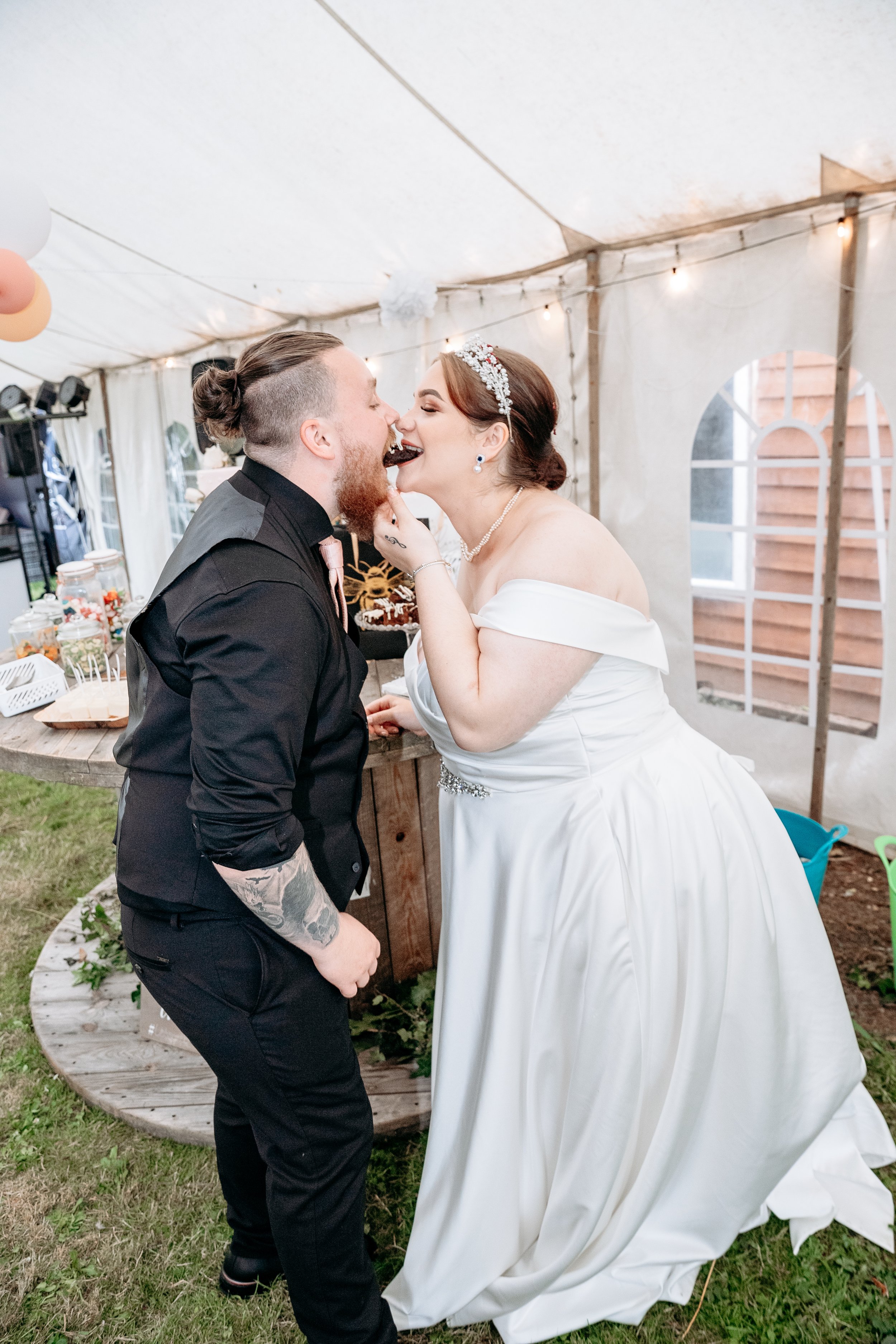 A bride and groom sharing a playful kiss at their wedding reception inside a tent.