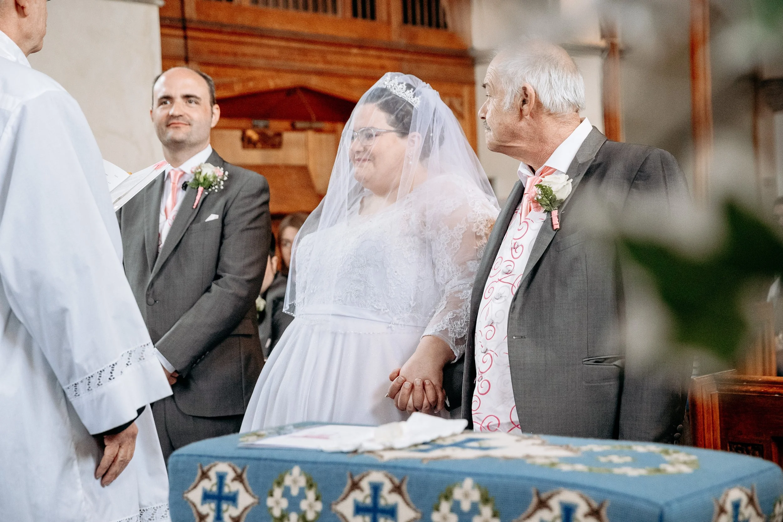 Bride and her father holding hands during wedding ceremony at church.