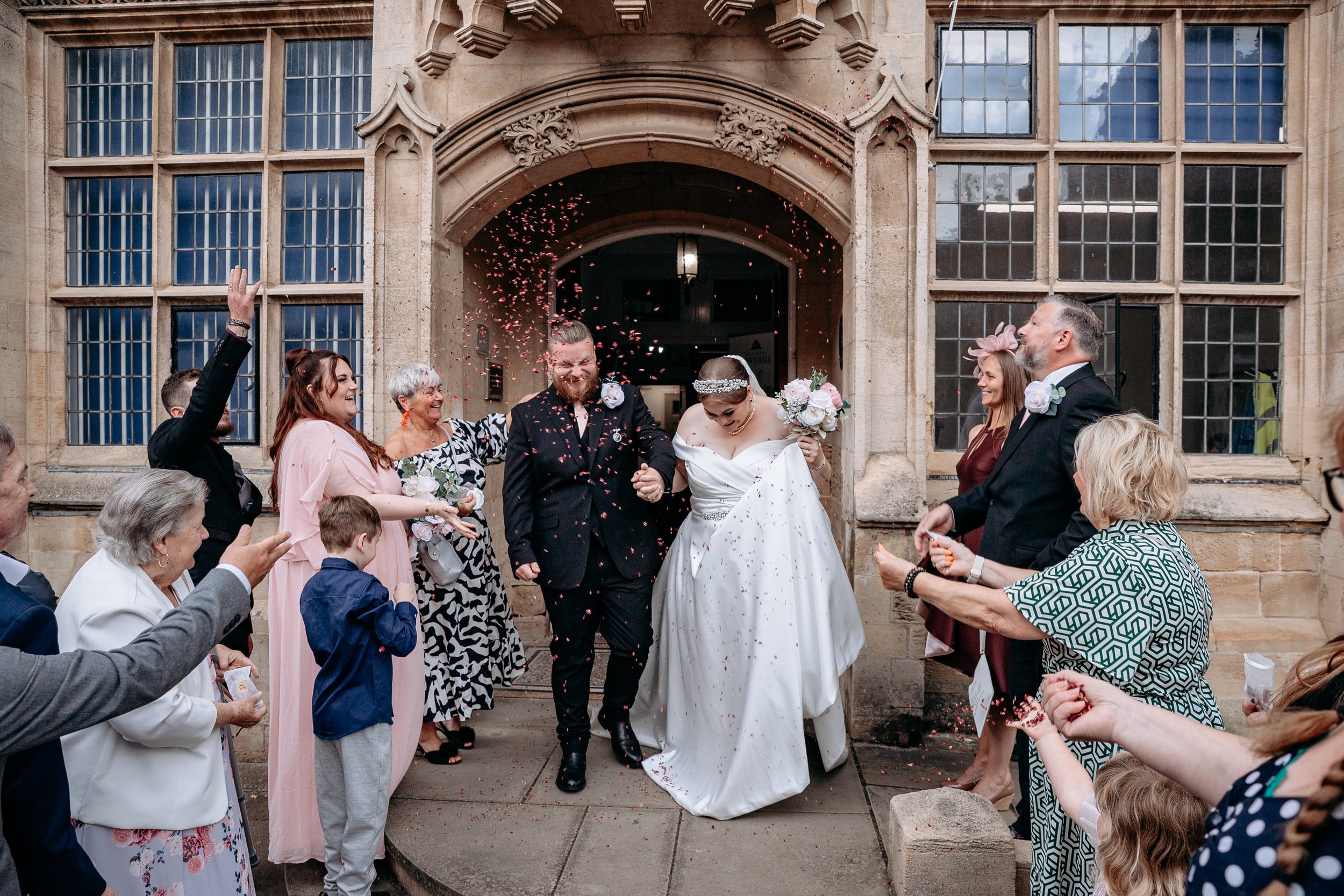 Bride and groom exiting a church surrounded by guests throwing confetti, celebrating their wedding.