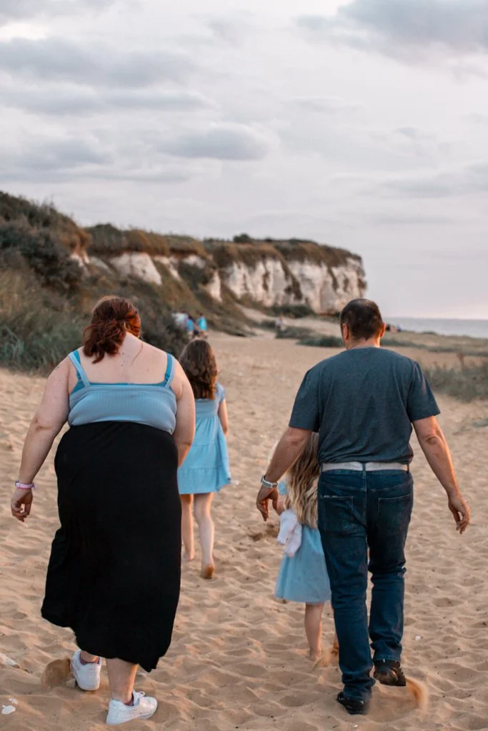 Family walking on sandy beach near cliffs