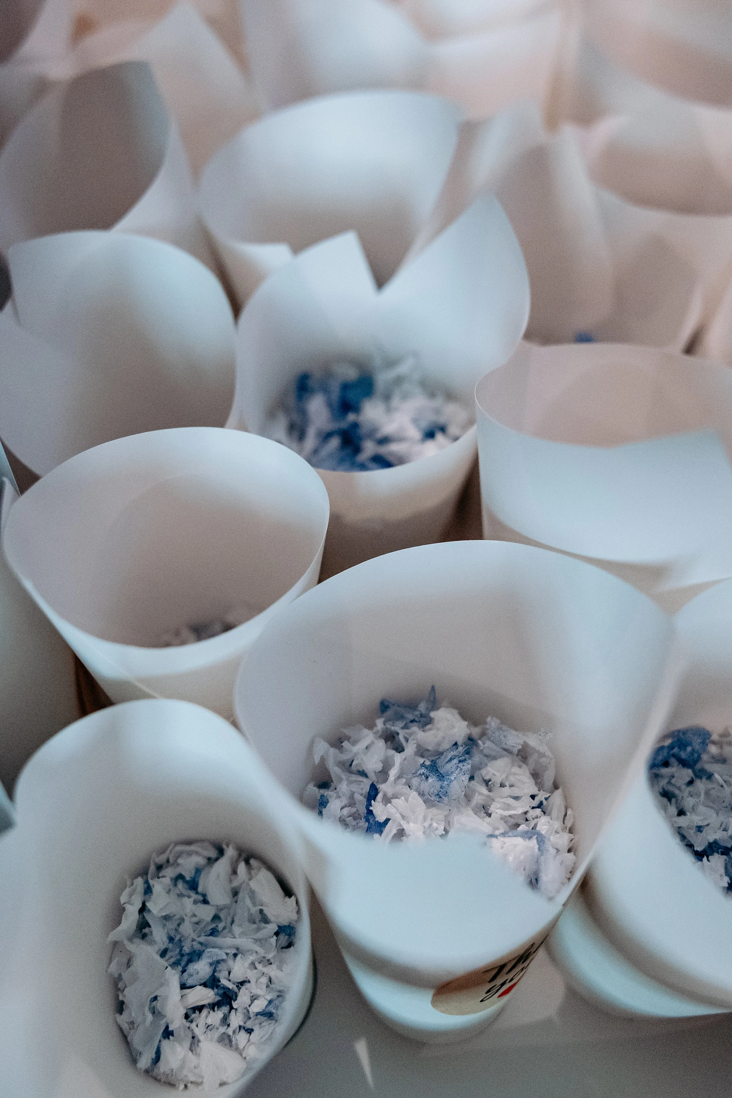 Multiple white paper cups filled with crumpled blue and white paper.