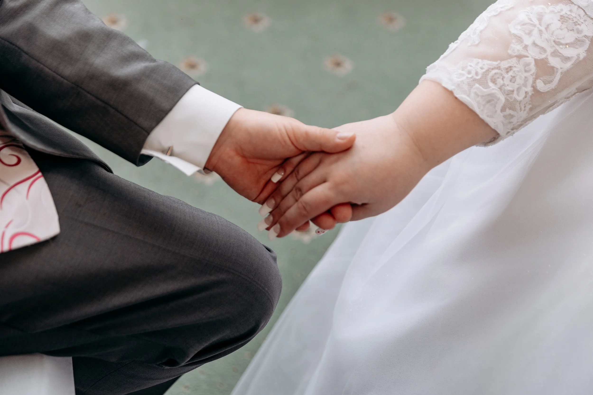 Close-up of a bride and groom holding hands during a wedding ceremony.