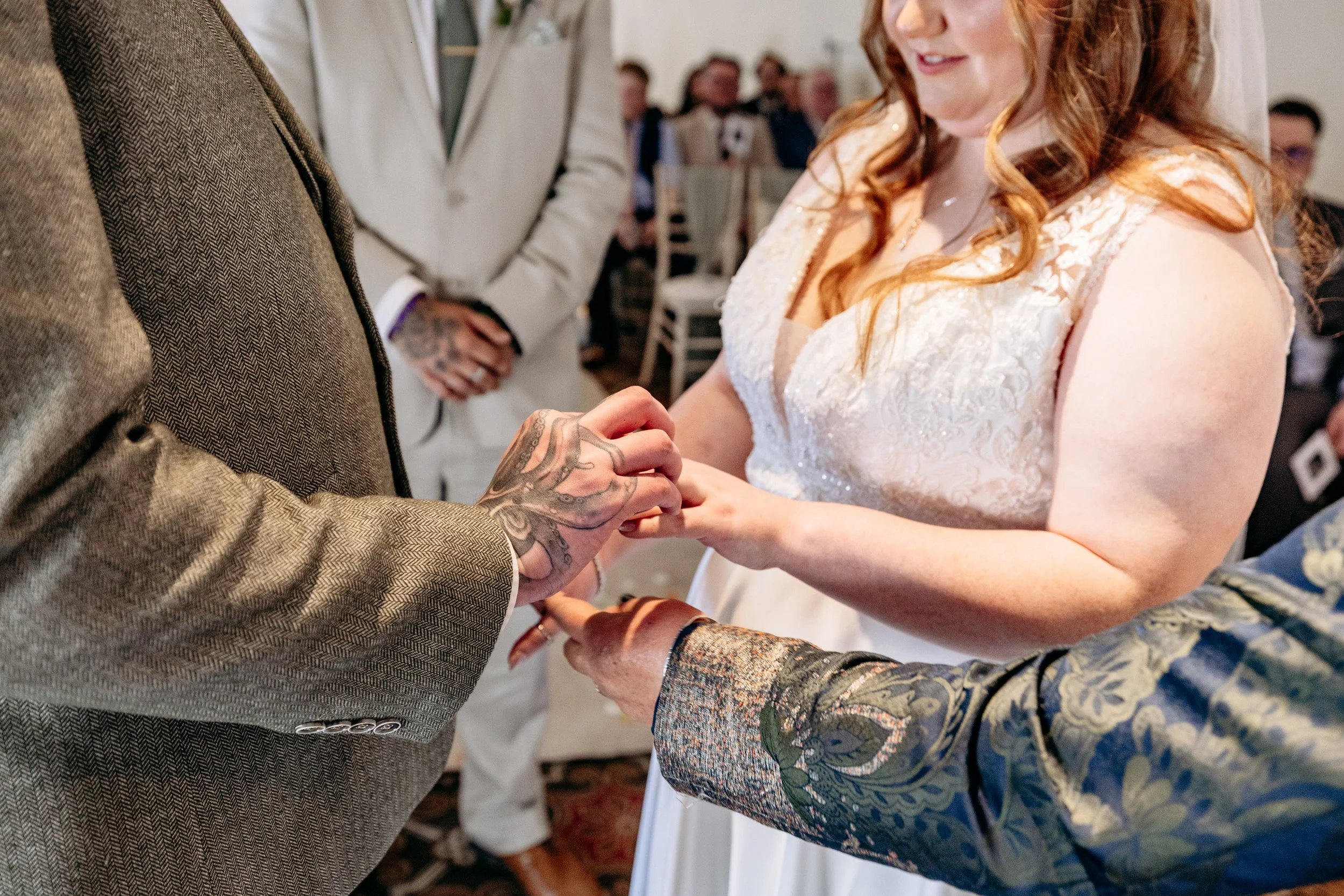 People exchanging wedding rings during a ceremony, with the focus on the hands of the bride and groom.