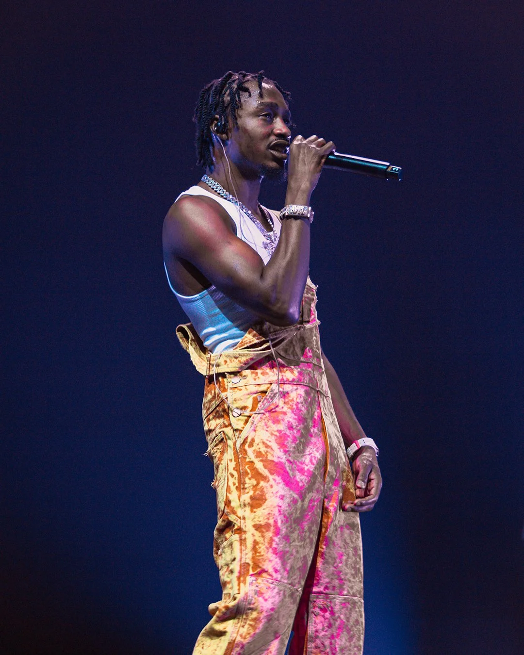 Musician performing on stage with microphone and colorful pants