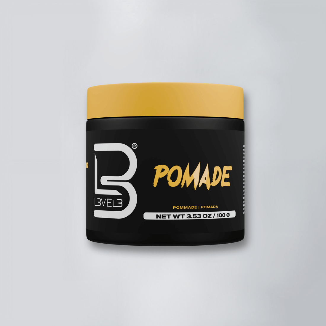 Black container of pomade hair styling product with yellow lid and white and yellow text on a light background.