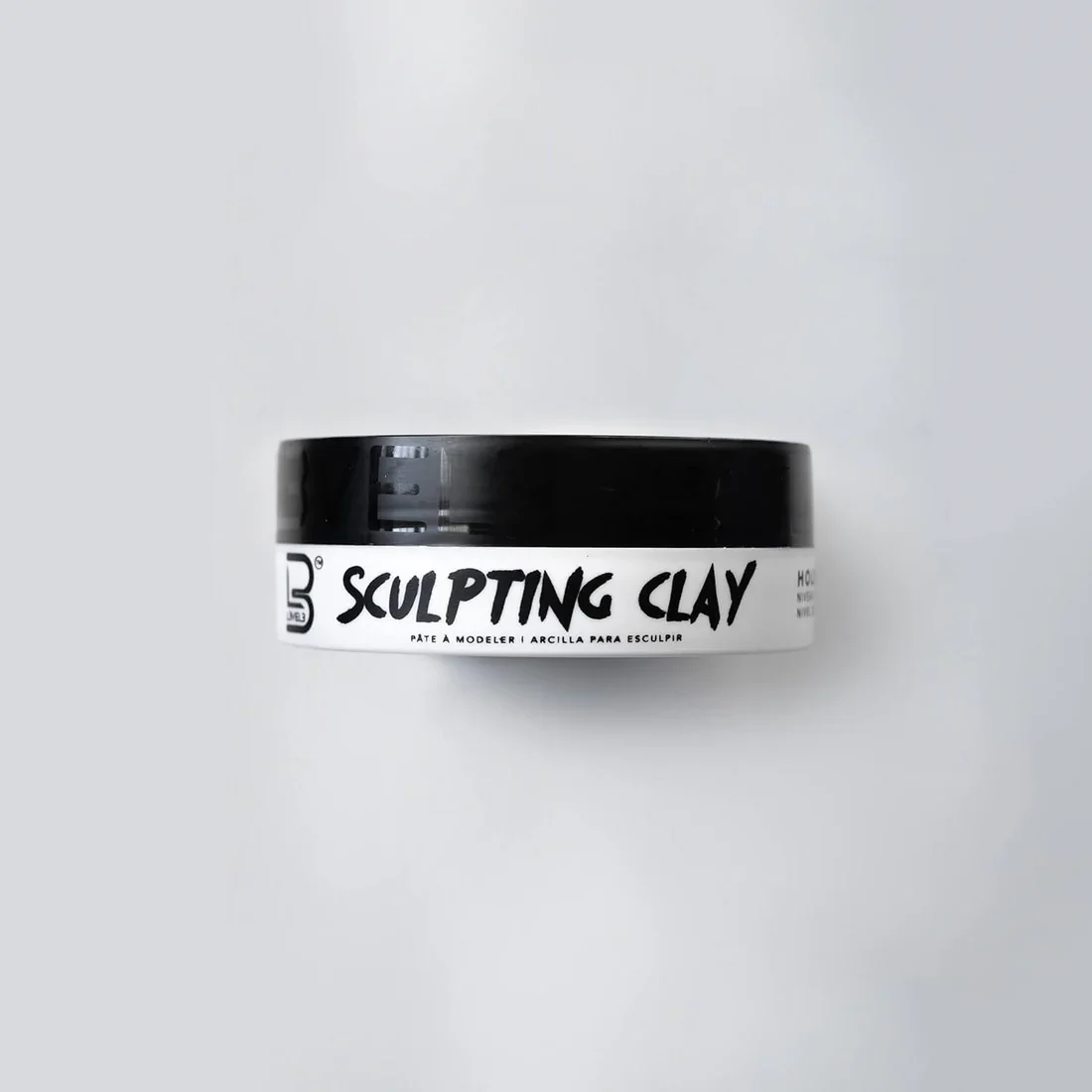 Black container of sculpting clay on a white surface