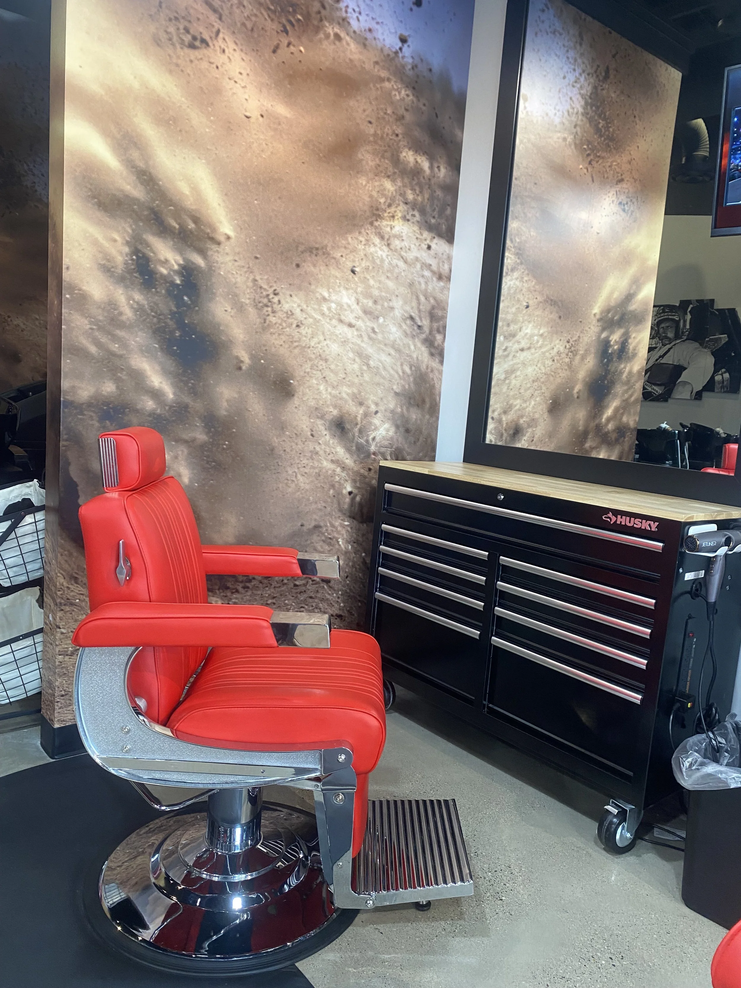 Red salon chair next to a black Husky tool chest with rolling drawers, positioned against a space-themed mural wall with planets and stars.