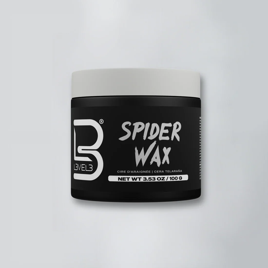 A black jar of Spider Wax with a white lid and label, placed on a light-colored surface.