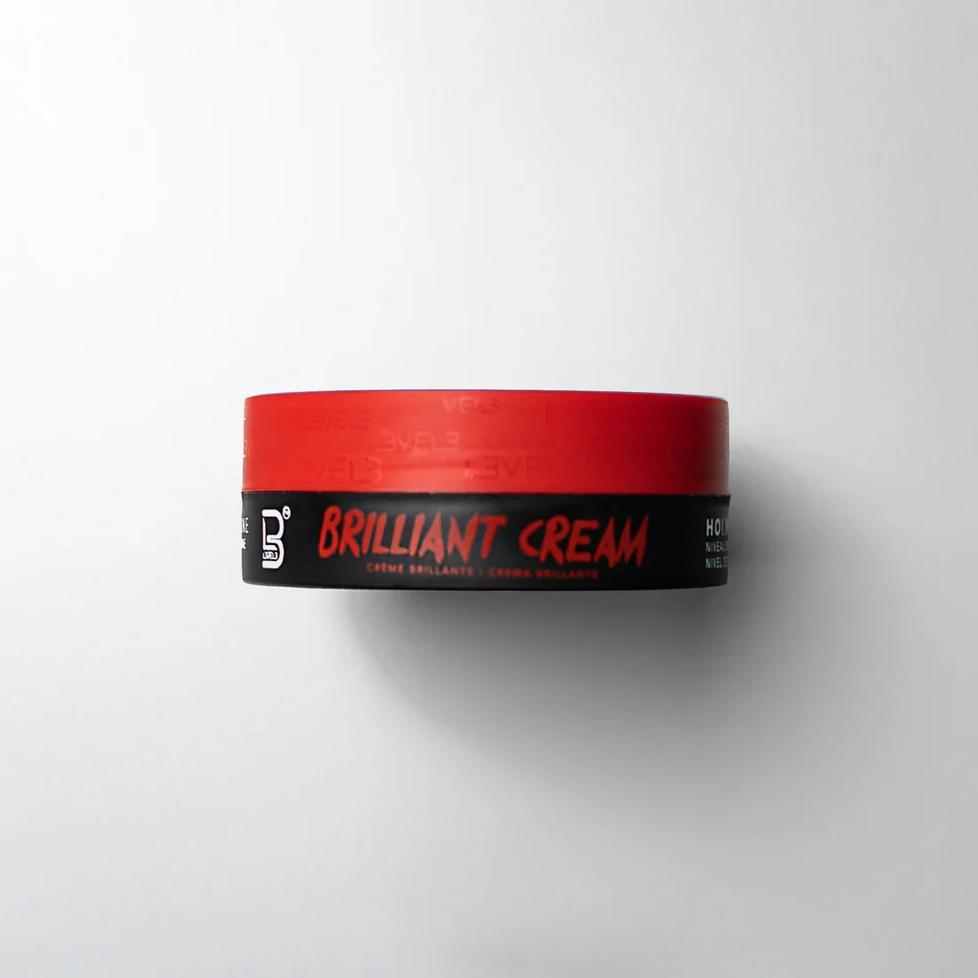 Container of Brillant Cream with red lid and black label on white background.