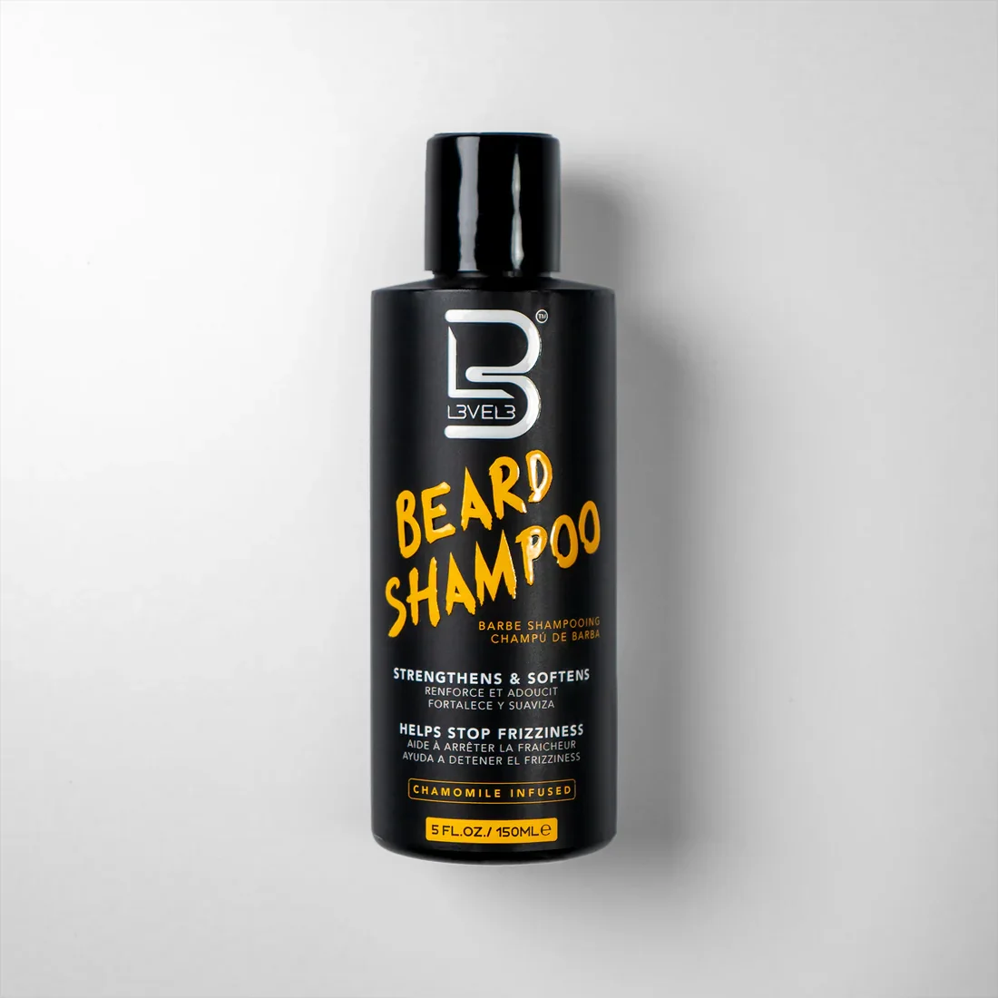 Black bottle of beard shampoo with a black cap, featuring white and yellow text, labeled as beard shampoo infused with chamomile, designed to strengthen, soften, and help stop frizzing.