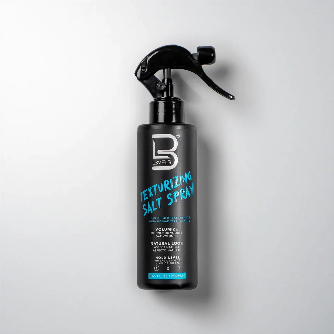 A black spray bottle labeled 'Texturizing Salt Spray' with a trigger spray nozzle, standing against a white background.