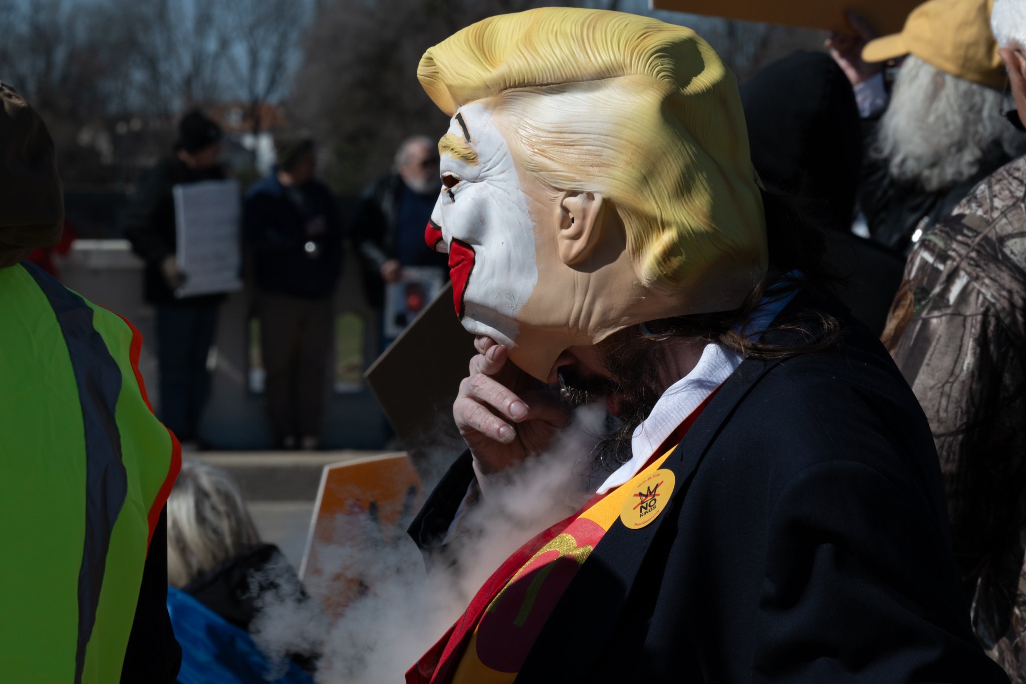 A protester releases vape smoke below a painted Donald Trump mask during the ‘No Kings 3’ protest March 28 at the Fallen Heroes Memorial Bridge.