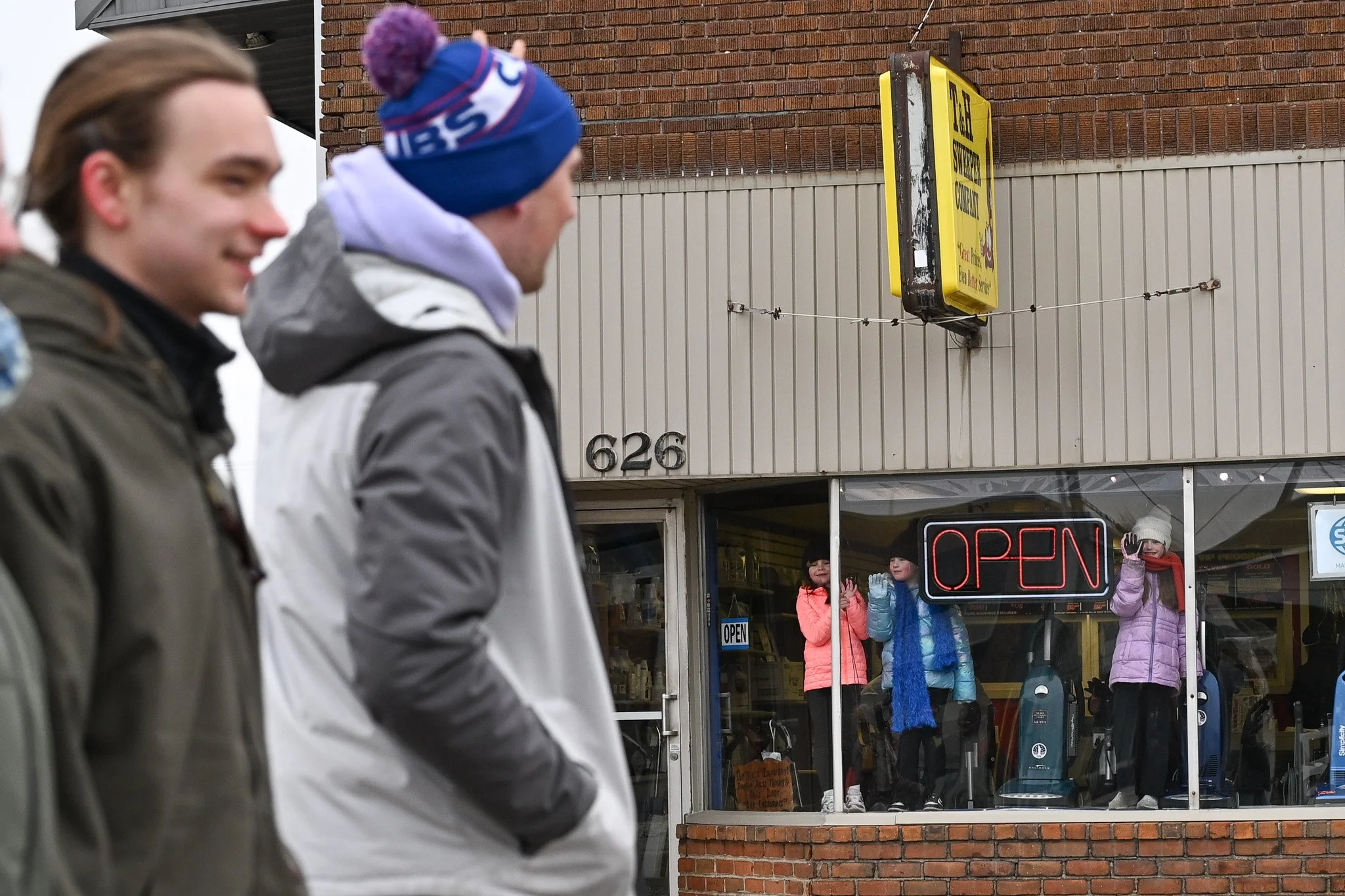 Young spectators watch through a storefront window as attendees of Muncie Mission's Walk a Mile in My Shoes event walk past Feb. 21 in Muncie, Indiana. Ryan Fleek, DN