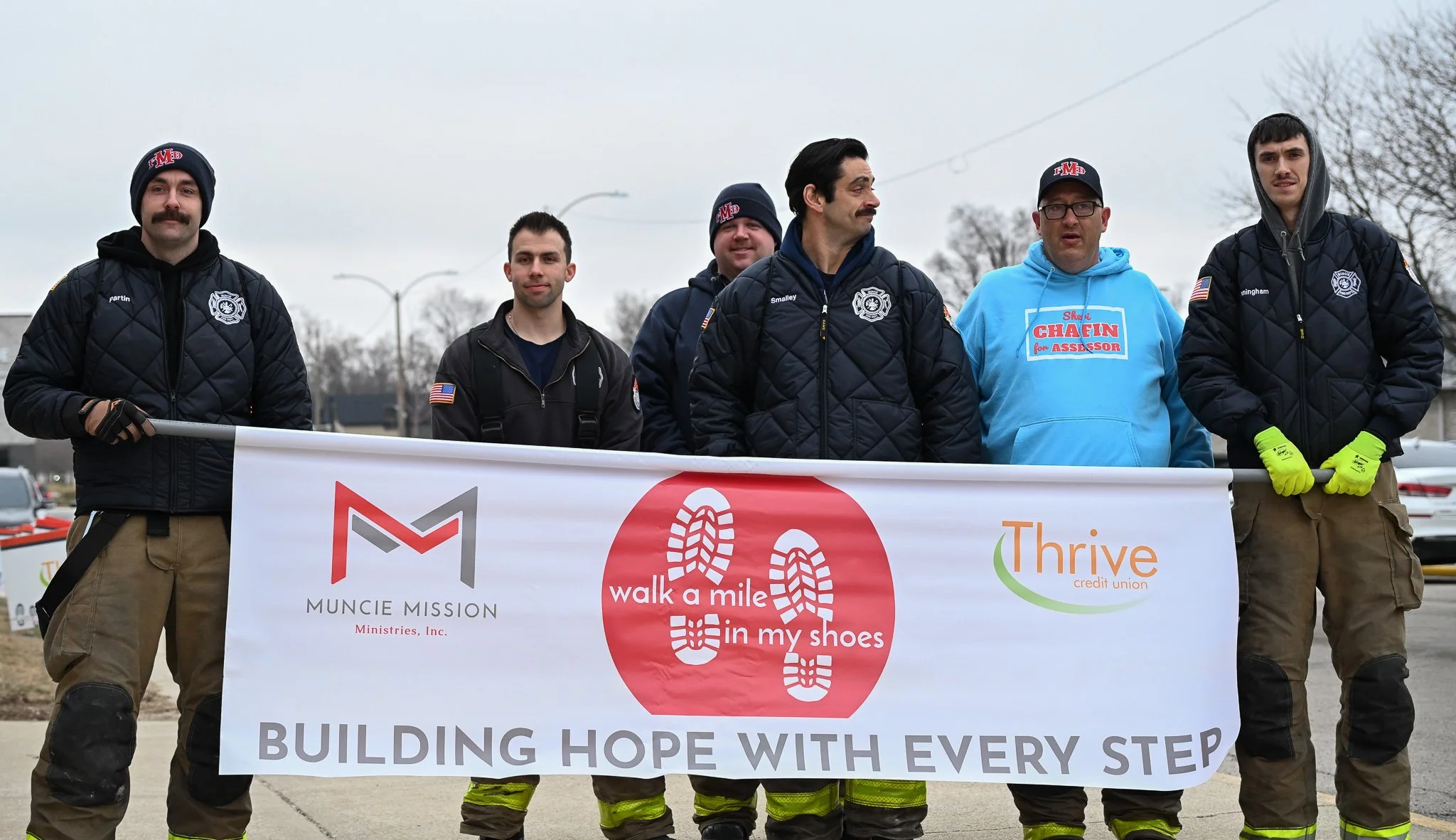 Firefighters of the Muncie Fire Department hold a banner in the front of the Muncie Mission Walk a Mile in My Shoes event Feb. 21 in Muncie, Indiana. 