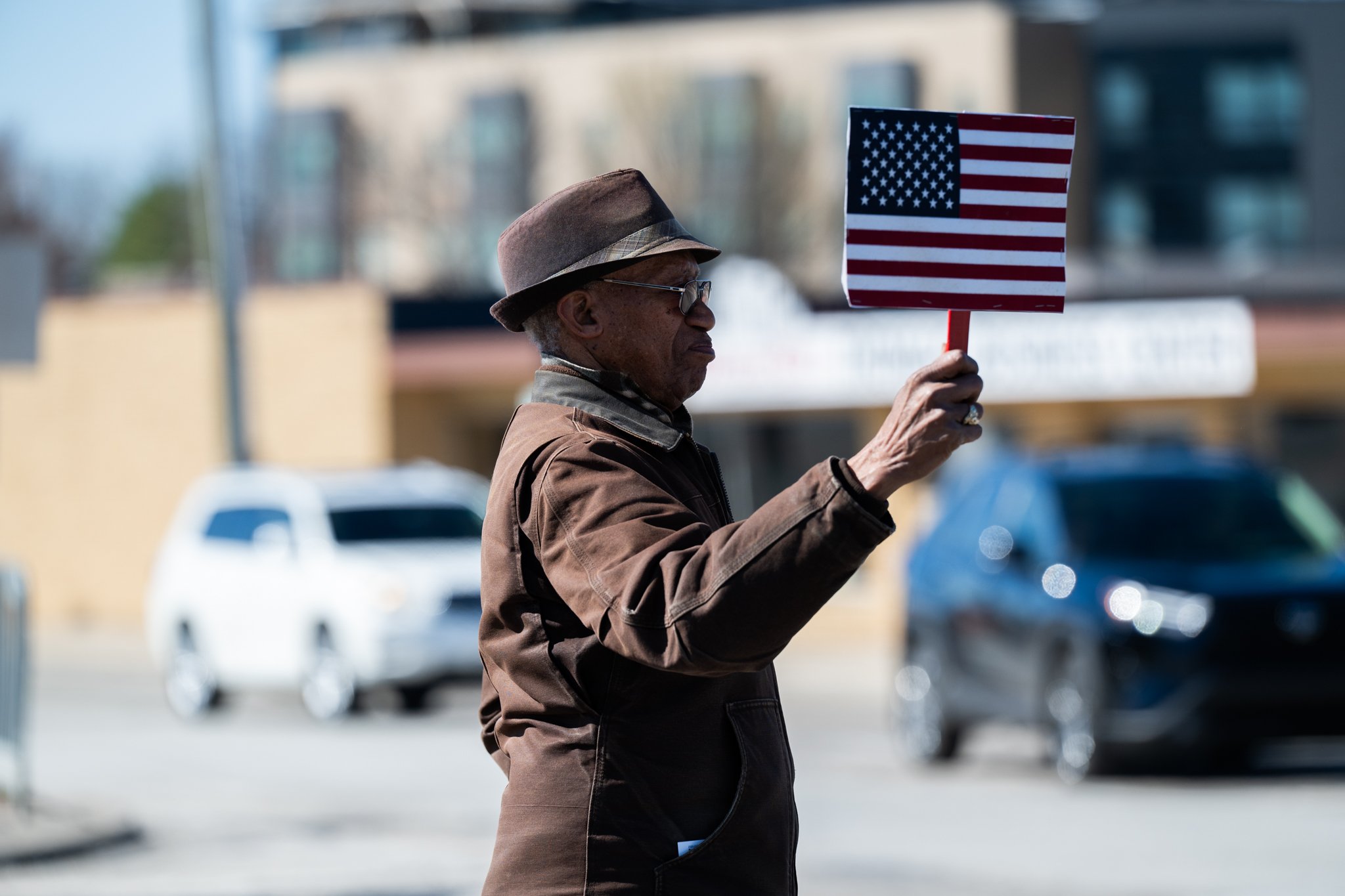 A protester holds a small American flag sign during the ‘No Kings 3’ protest March 28 at the Fallen Heroes Memorial Bridge.